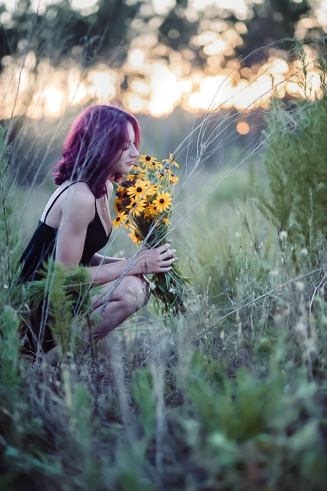 Purple-haired figure in a meadow smelling yellow wildflowers at sunset with dreamy bokeh lighting.