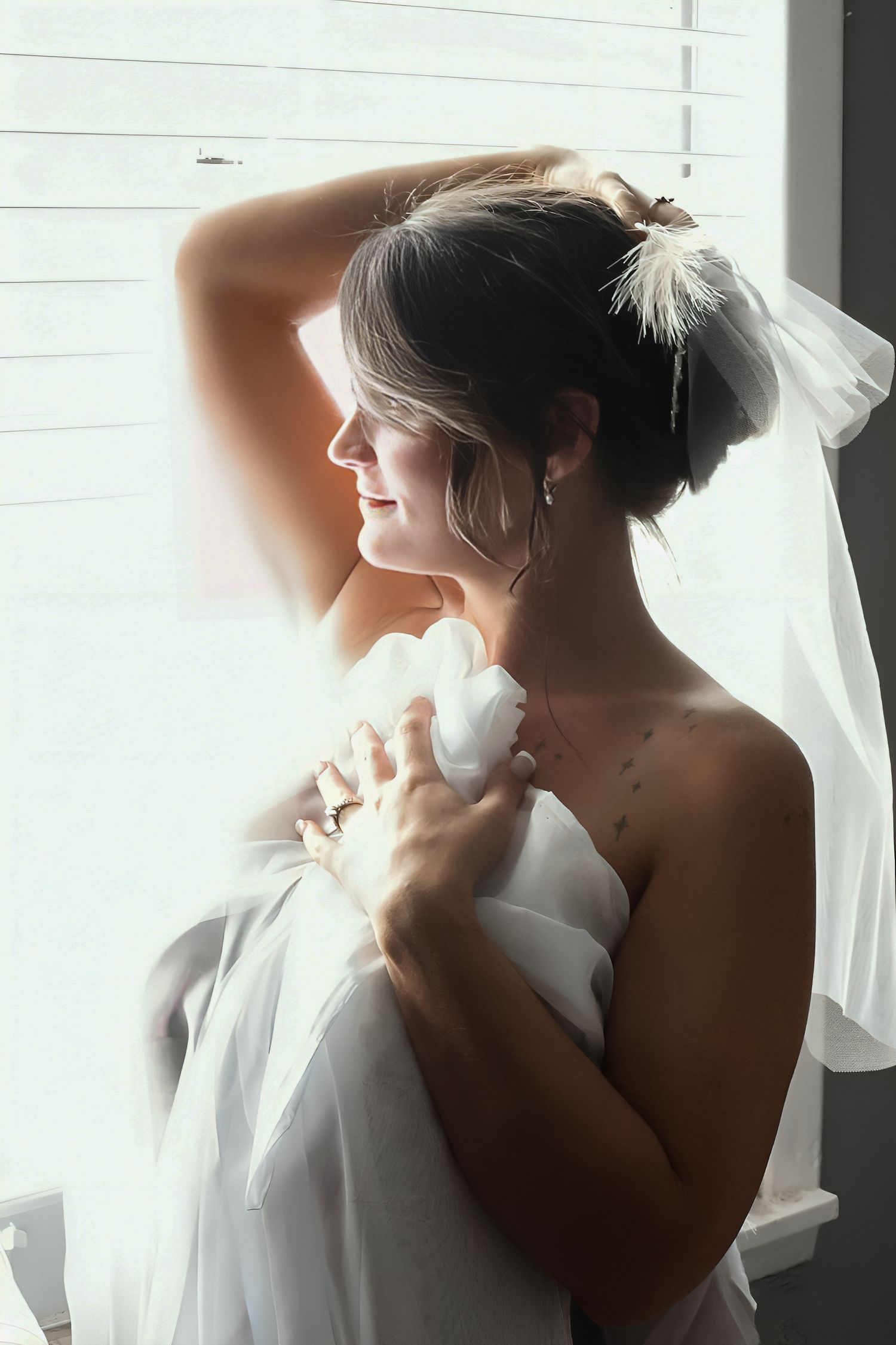 A bride in a white wedding dress and veil stands in silhouette against a bright window in a series of artistic photos.