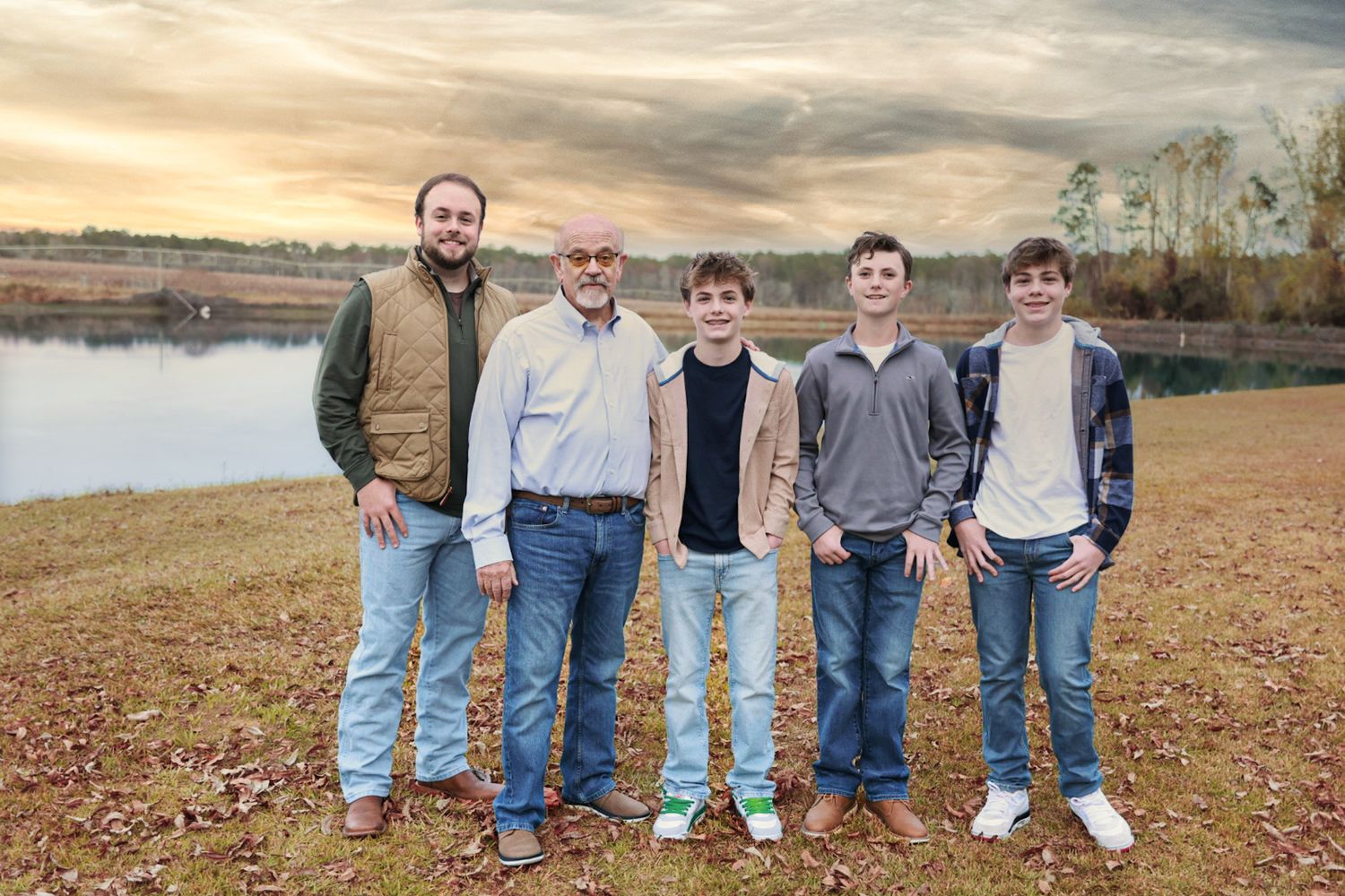 Family group standing together on gravel path during golden hour with dramatic cloudy sky.