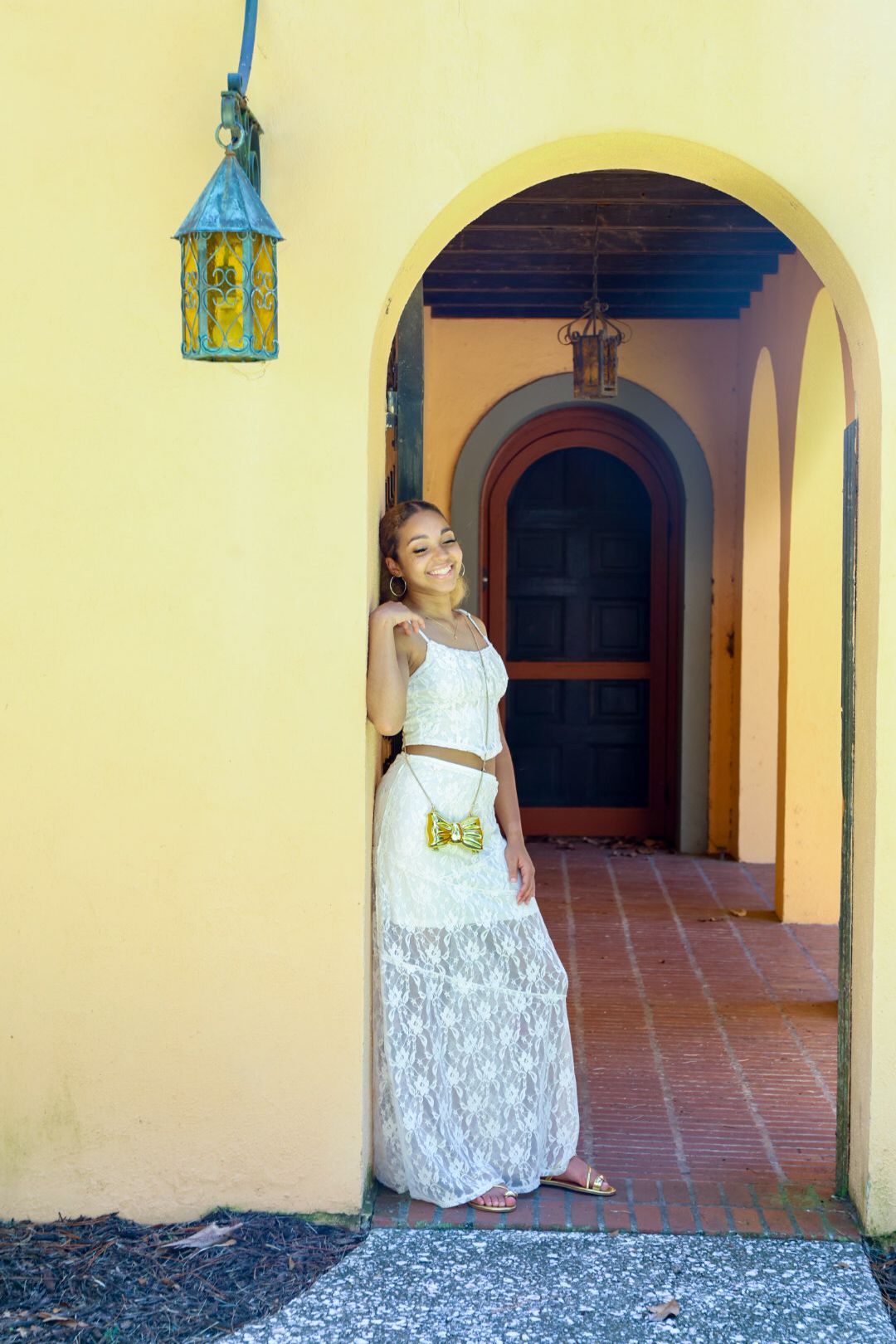 A series of four photos showing someone in a white lace dress posing in an arched yellow hallway with terracotta floors.