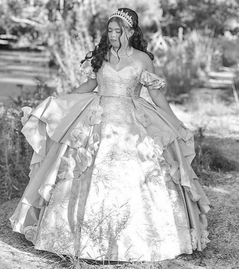Young woman in elegant ball gown and tiara poses gracefully outdoors in black and white quinceañera photo.