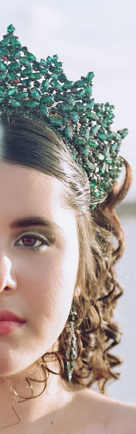 A stunning emerald crystal headpiece adorns wavy hair in an artistic beauty portrait.