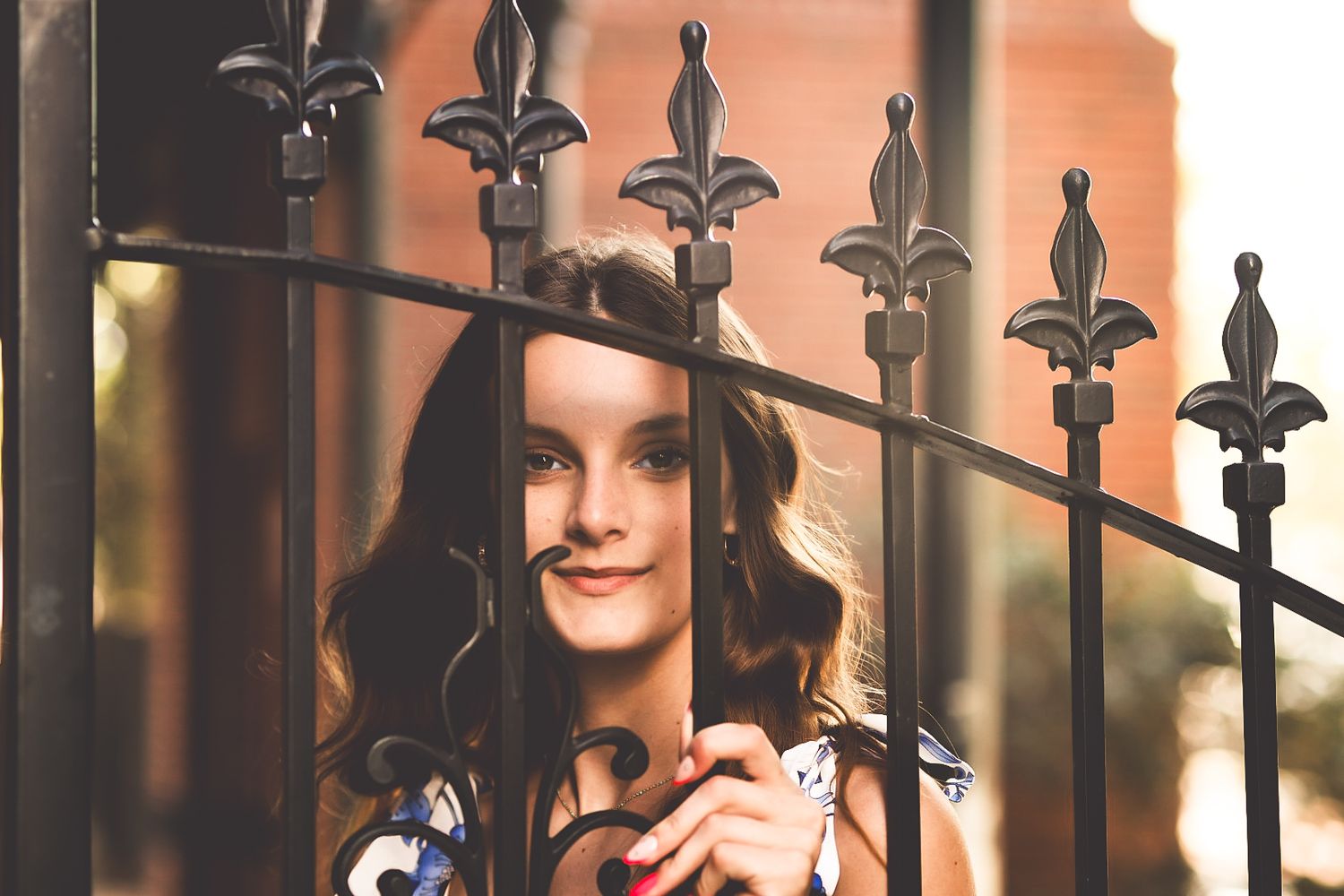 Woman in a casual outfit poses against decorative iron railings in an urban setting.
