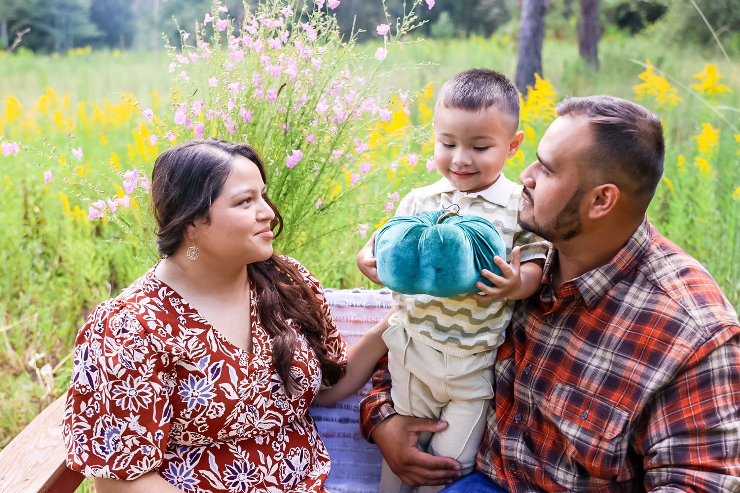 Family enjoying playful moments together in a sunny meadow with colorful wildflowers.