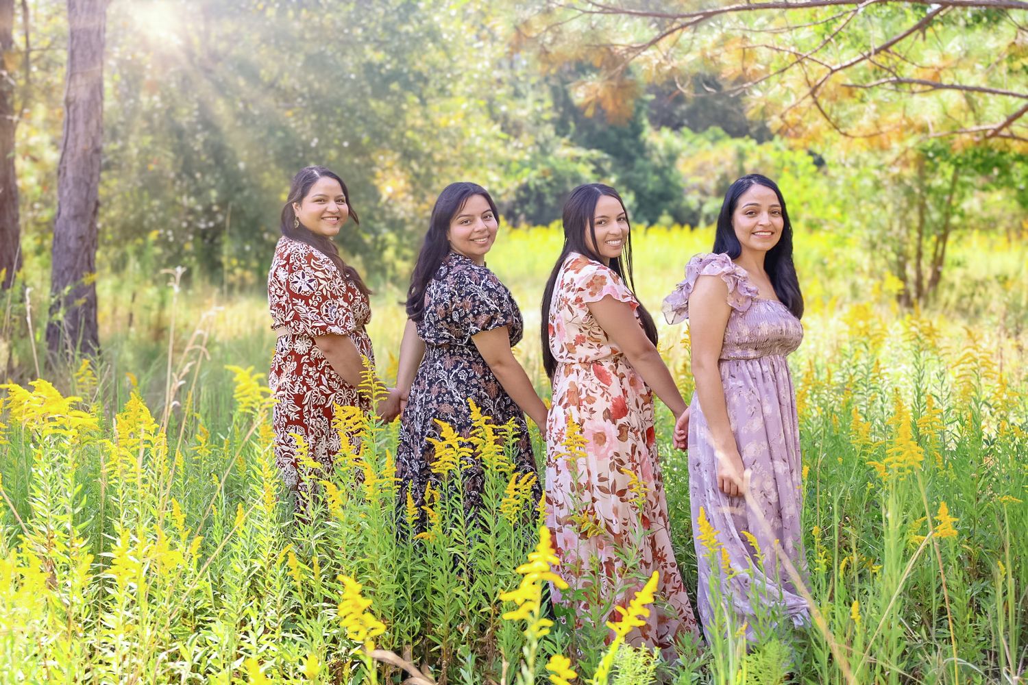 A group enjoys a sunny afternoon in a wildflower meadow with tall yellow blooms and trees in the background.