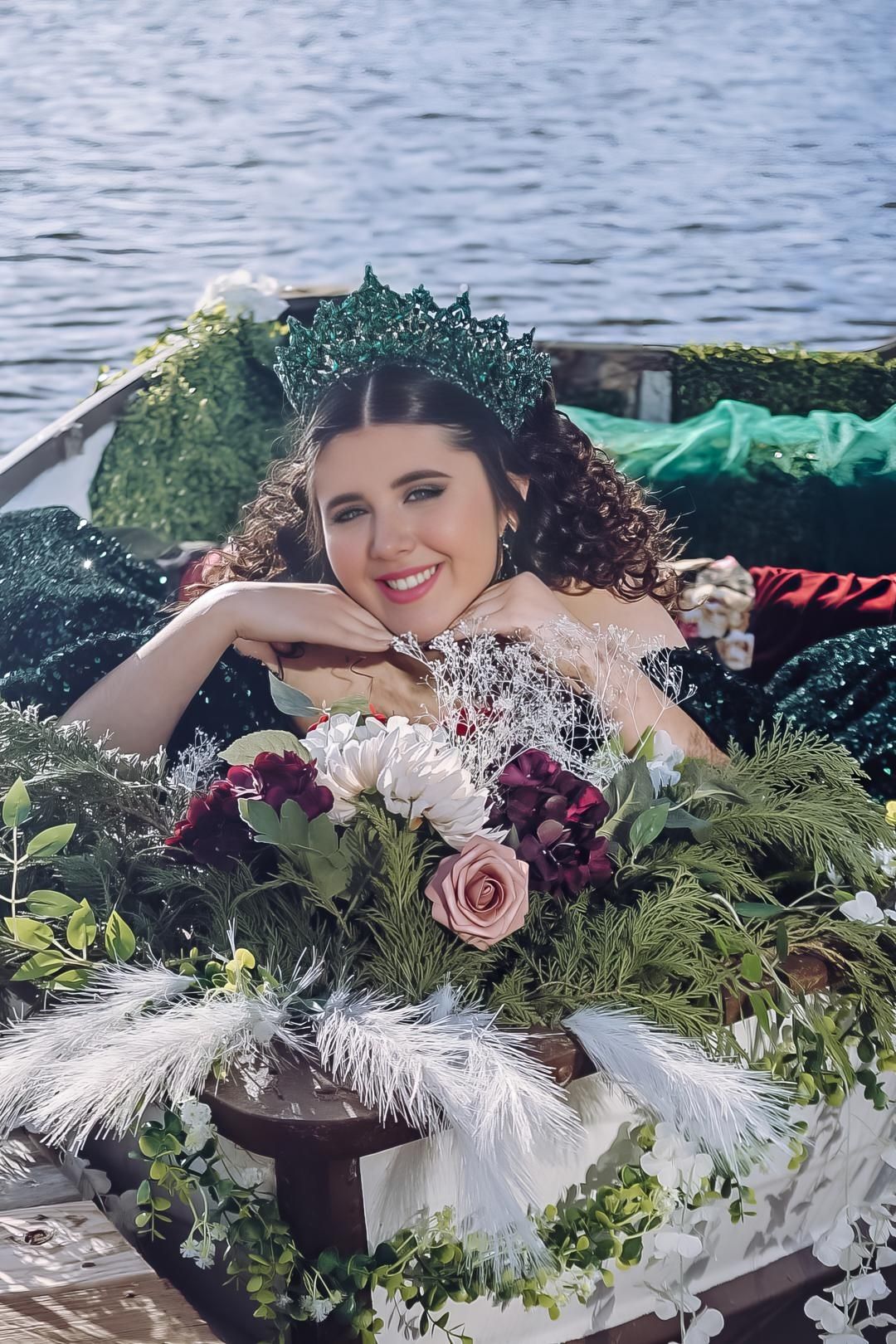 A decorative floral arrangement with white feathers and pink roses adorns a waterfront setting.