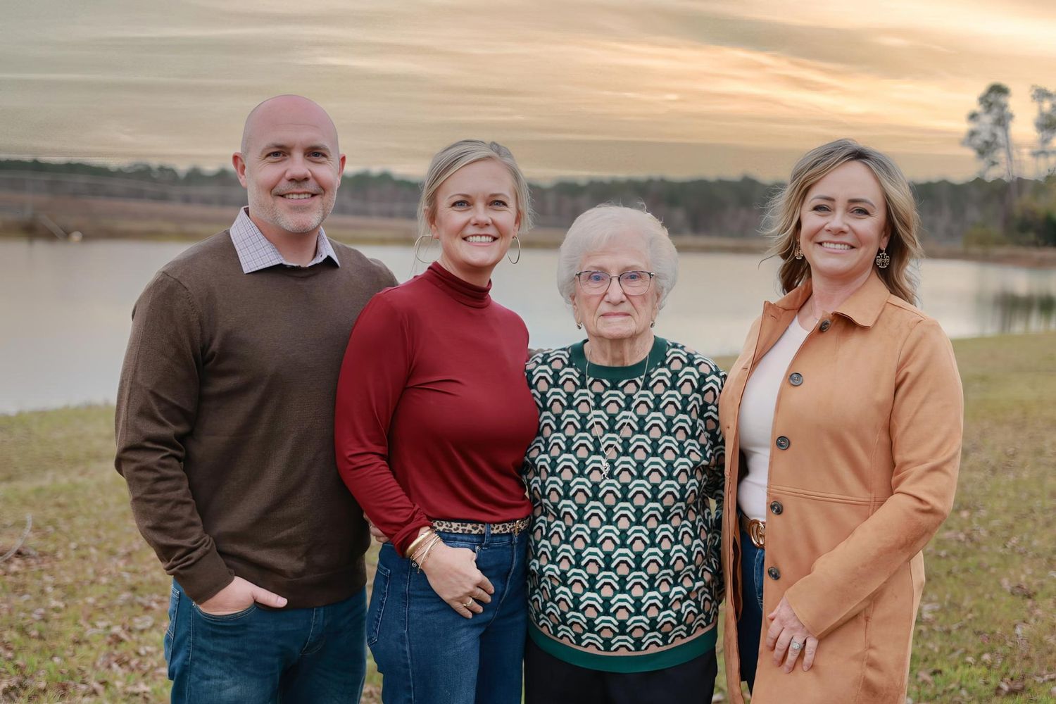 Group portrait of family members standing together outdoors during golden sunset hour.