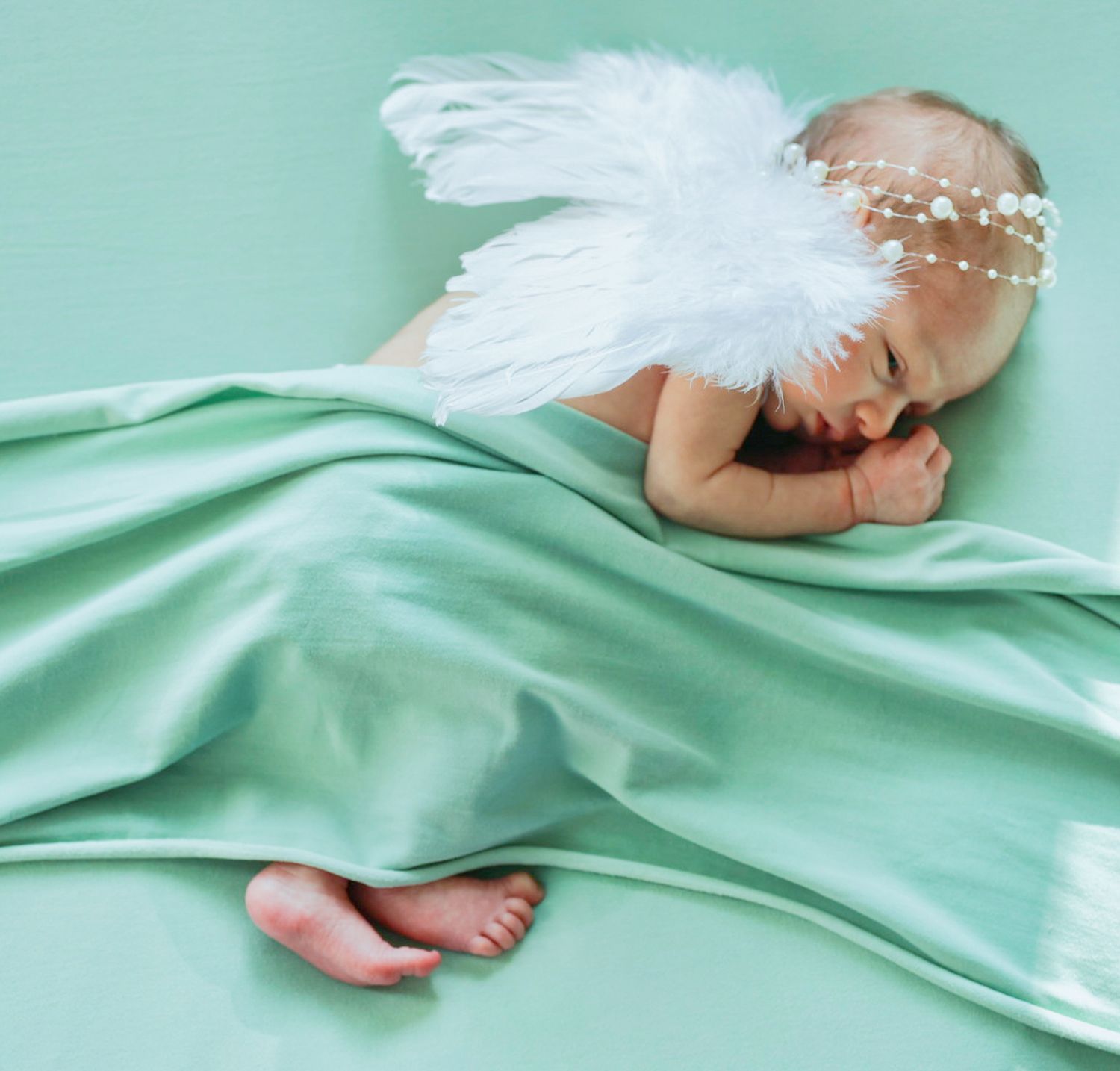 Feet emerging from under mint green bedding in a sequence showing movement under soft cotton sheets.