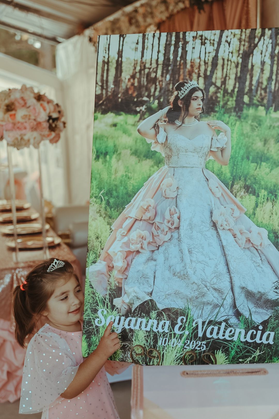 Young girl in pink dress stands beside a Quinceanera poster for Sryanna E Valencia dated 10.02.2025.