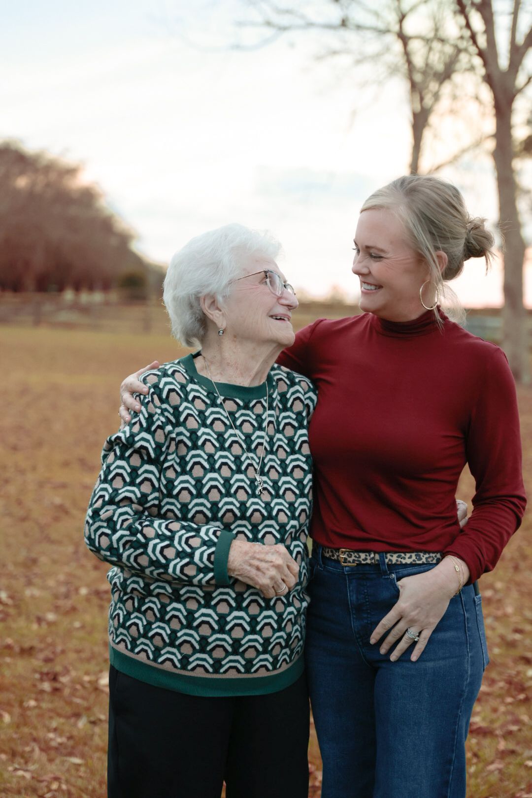 Two people share a joyful moment together while standing outdoors in casual attire during autumn.