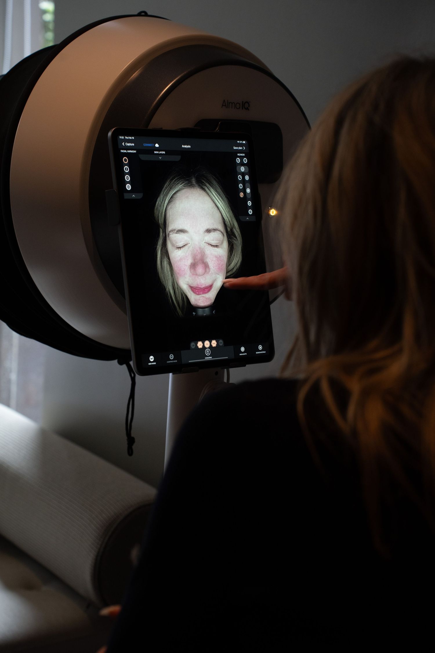 Woman reviewing facial analysis results on a VISIA complexion analysis machine screen in a skincare clinic.