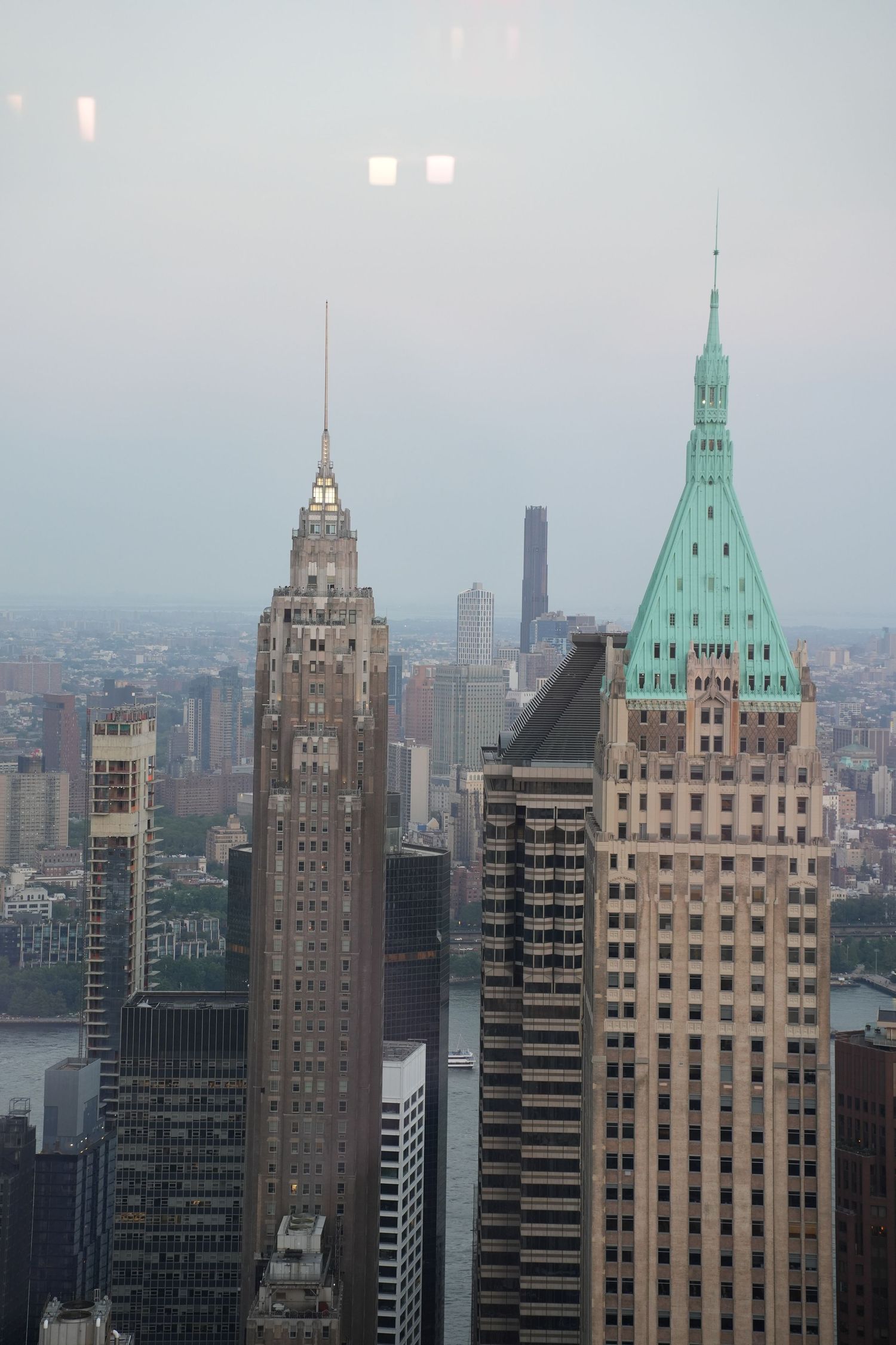 Aerial view of iconic New York City skyscrapers including buildings with green copper spires at dusk.