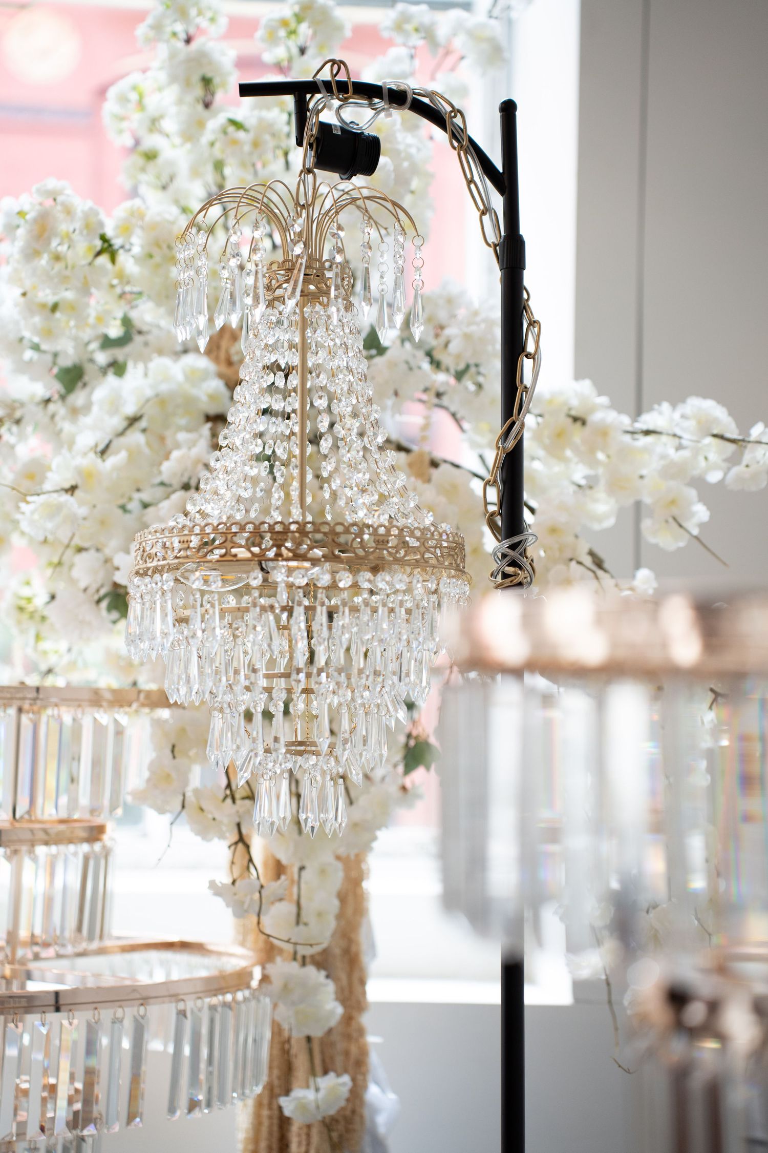 Gold crystal chandelier centerpiece with cascading crystals surrounded by white cherry blossom floral arrangements.