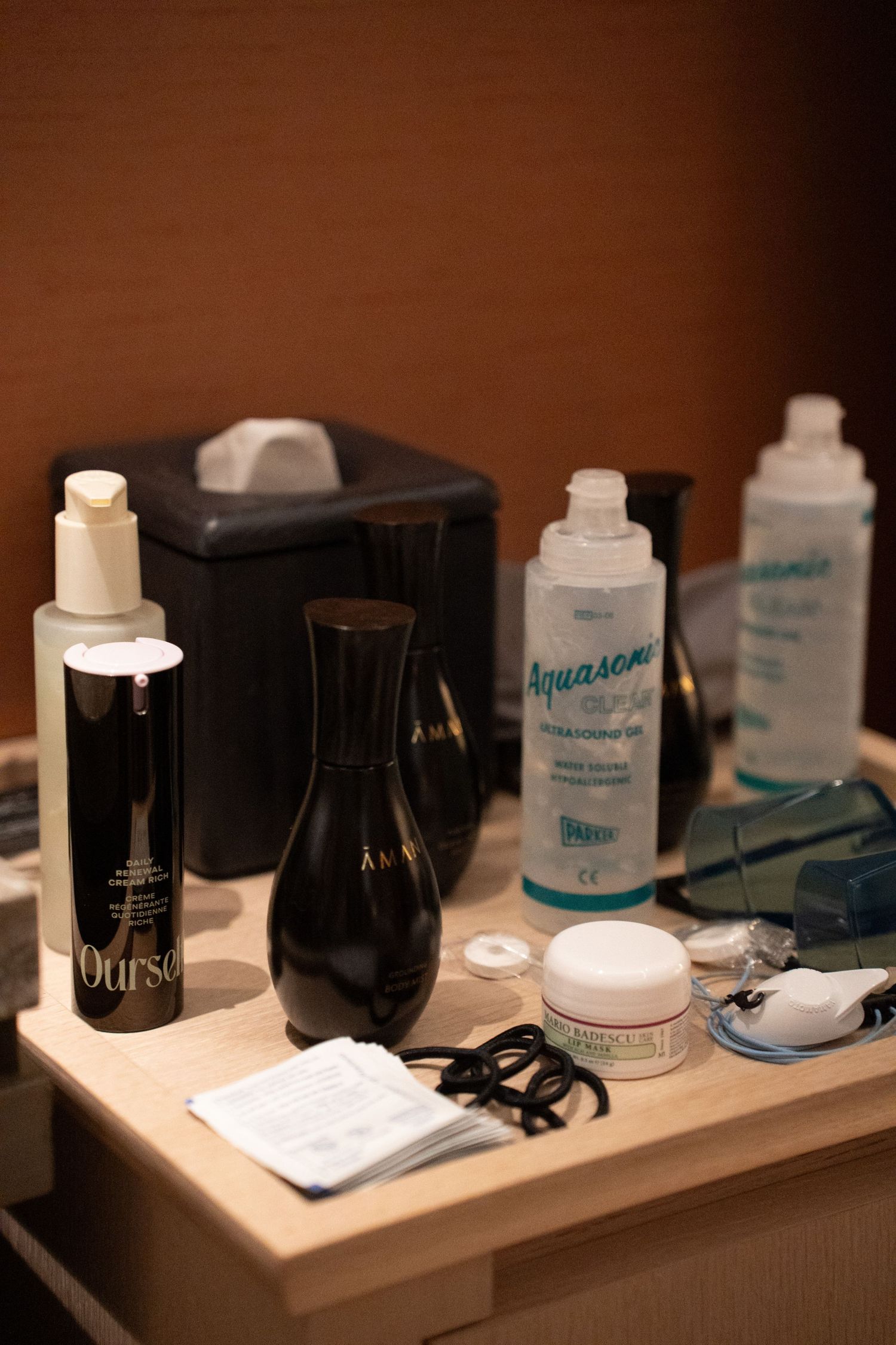 Skincare products including Aquasonic gel and Ourse serum arranged on a wooden tray in a spa treatment room.