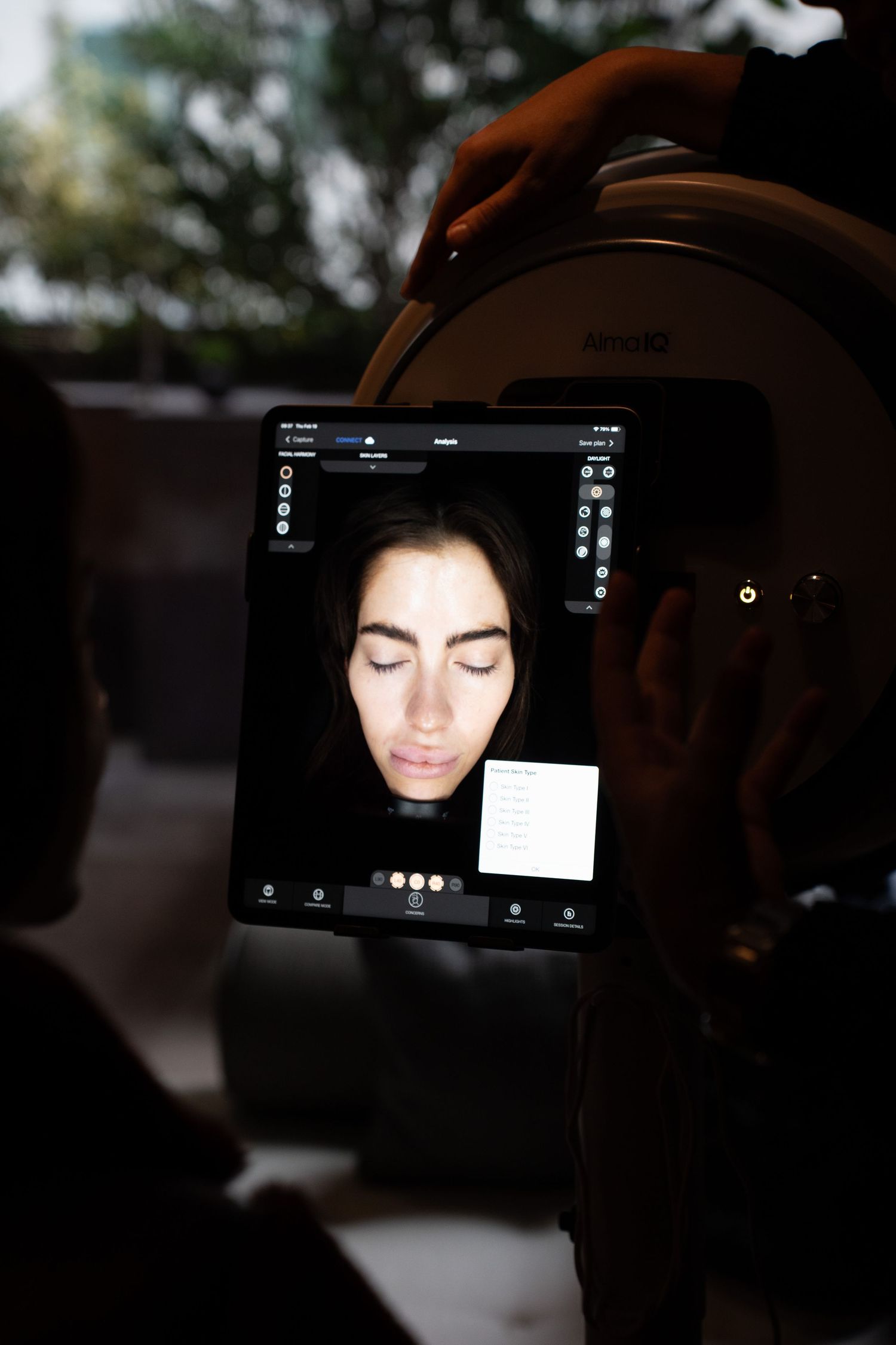 Skin analysis being performed using an Alma IQ tablet device on a woman's face.