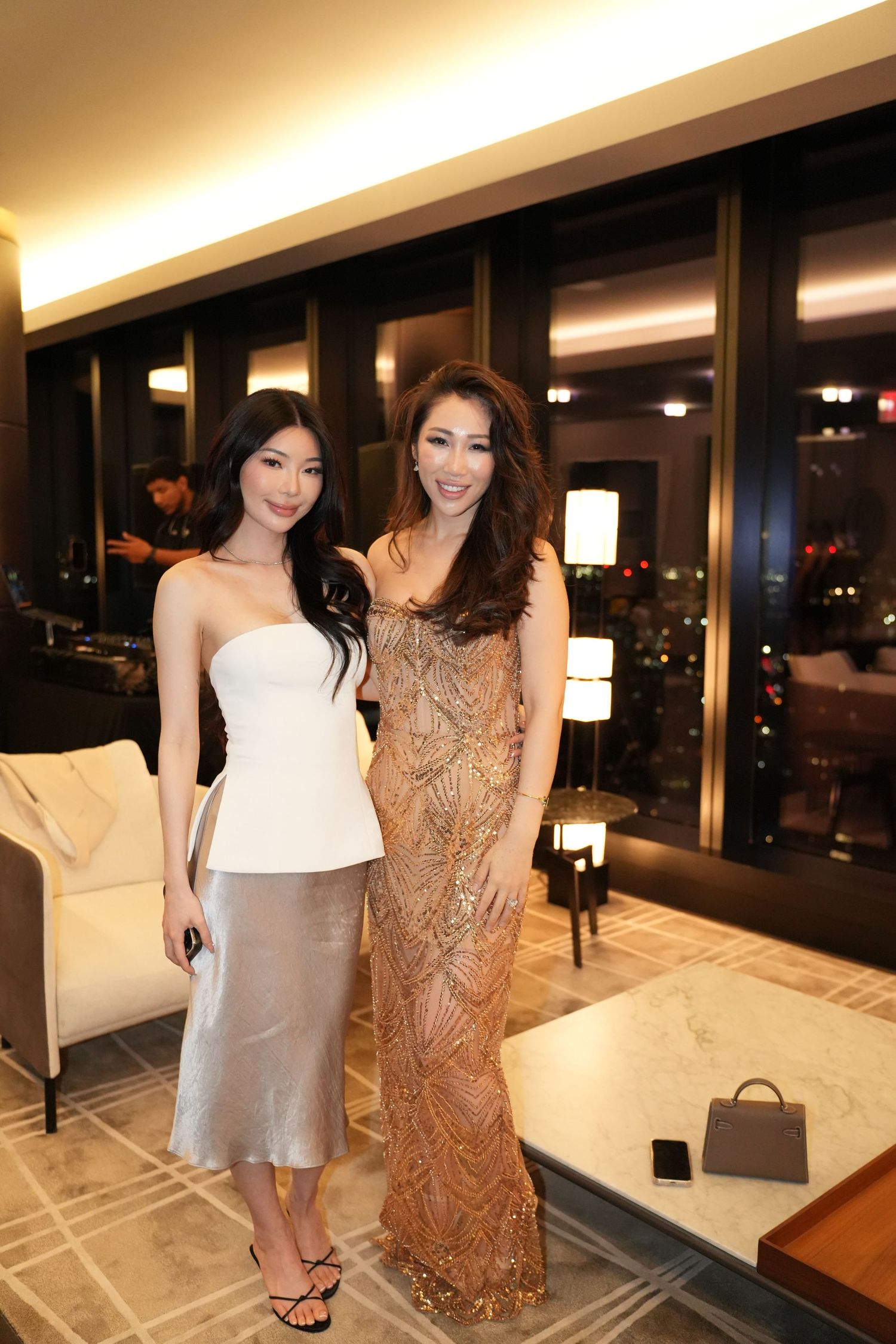 Two elegantly dressed women posing together at a sophisticated upscale evening event.
