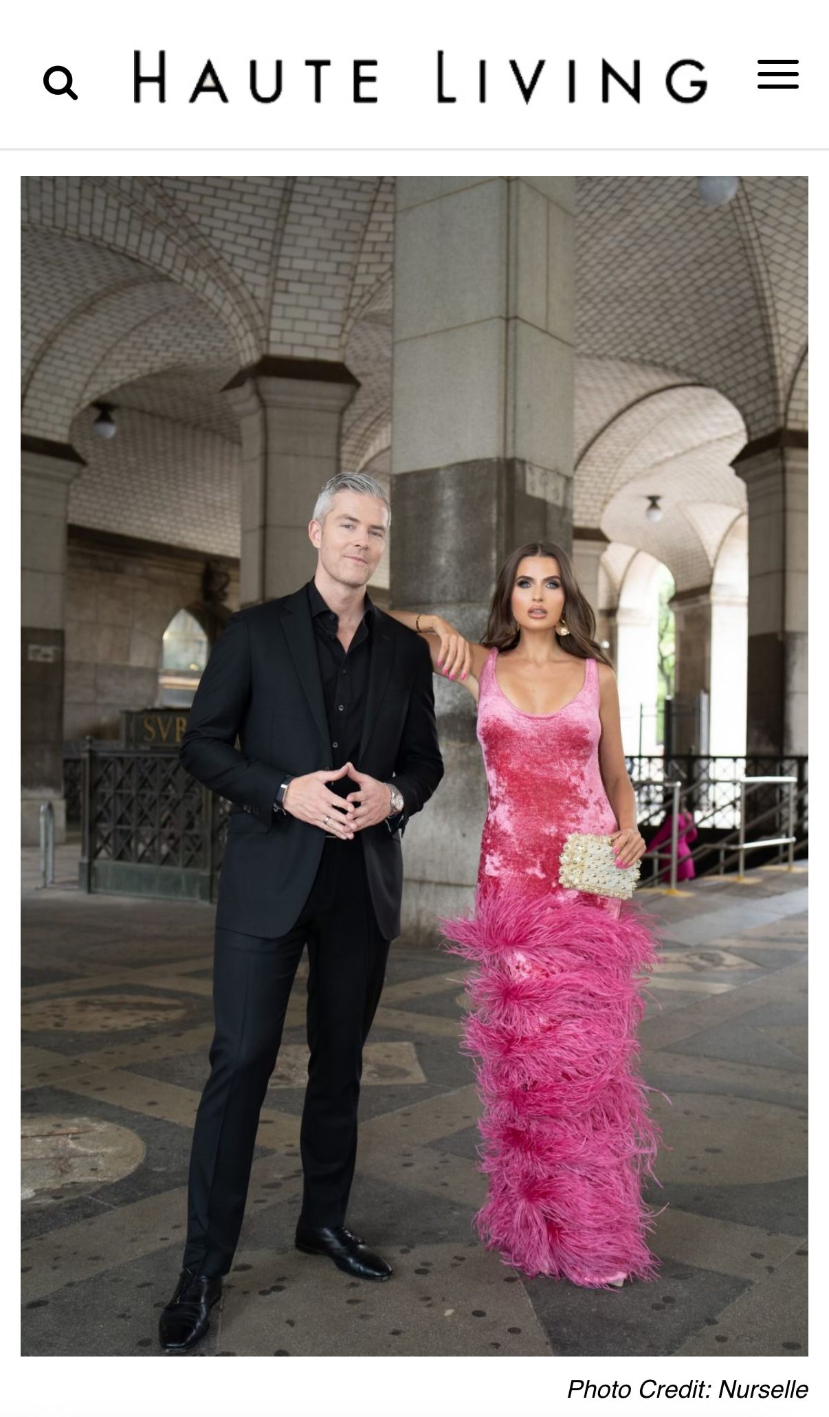 Real estate broker Ryan Serhant poses with a woman in a pink feather gown at Haute Living event.