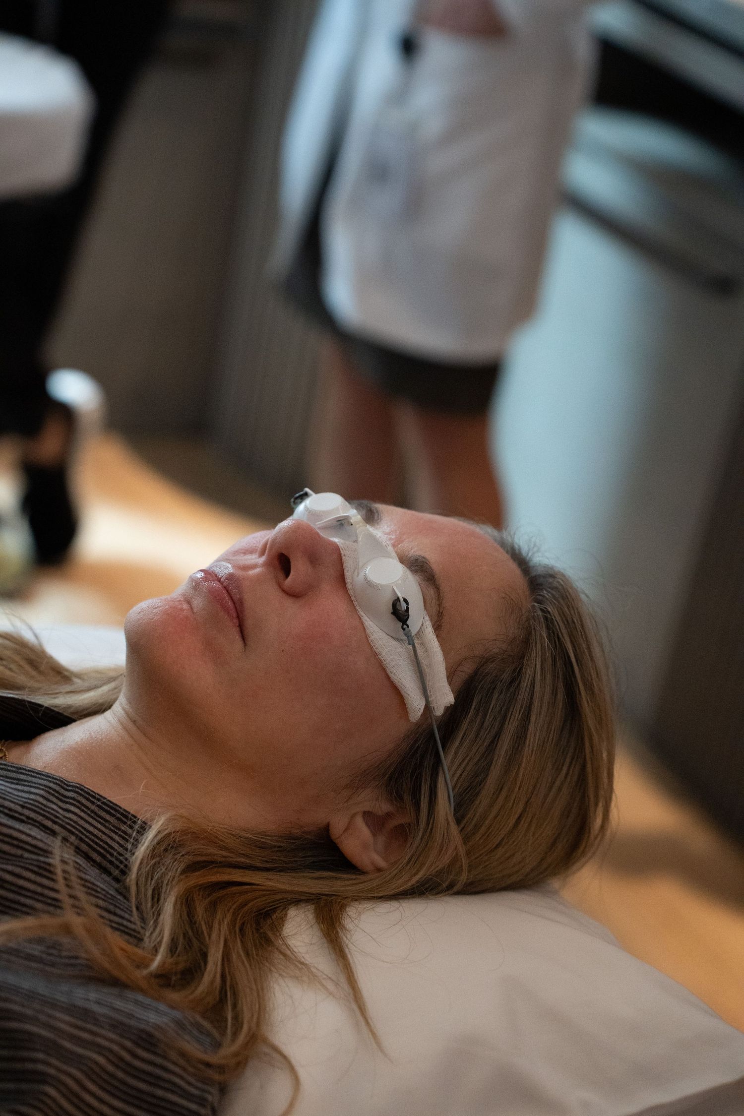 Woman lying on treatment table wearing protective eye shields during a facial laser treatment procedure.