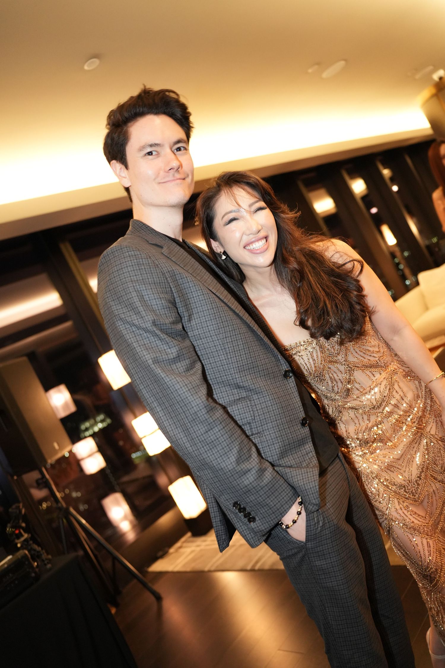 Smiling couple posing together at a glamorous indoor evening party in formal attire.