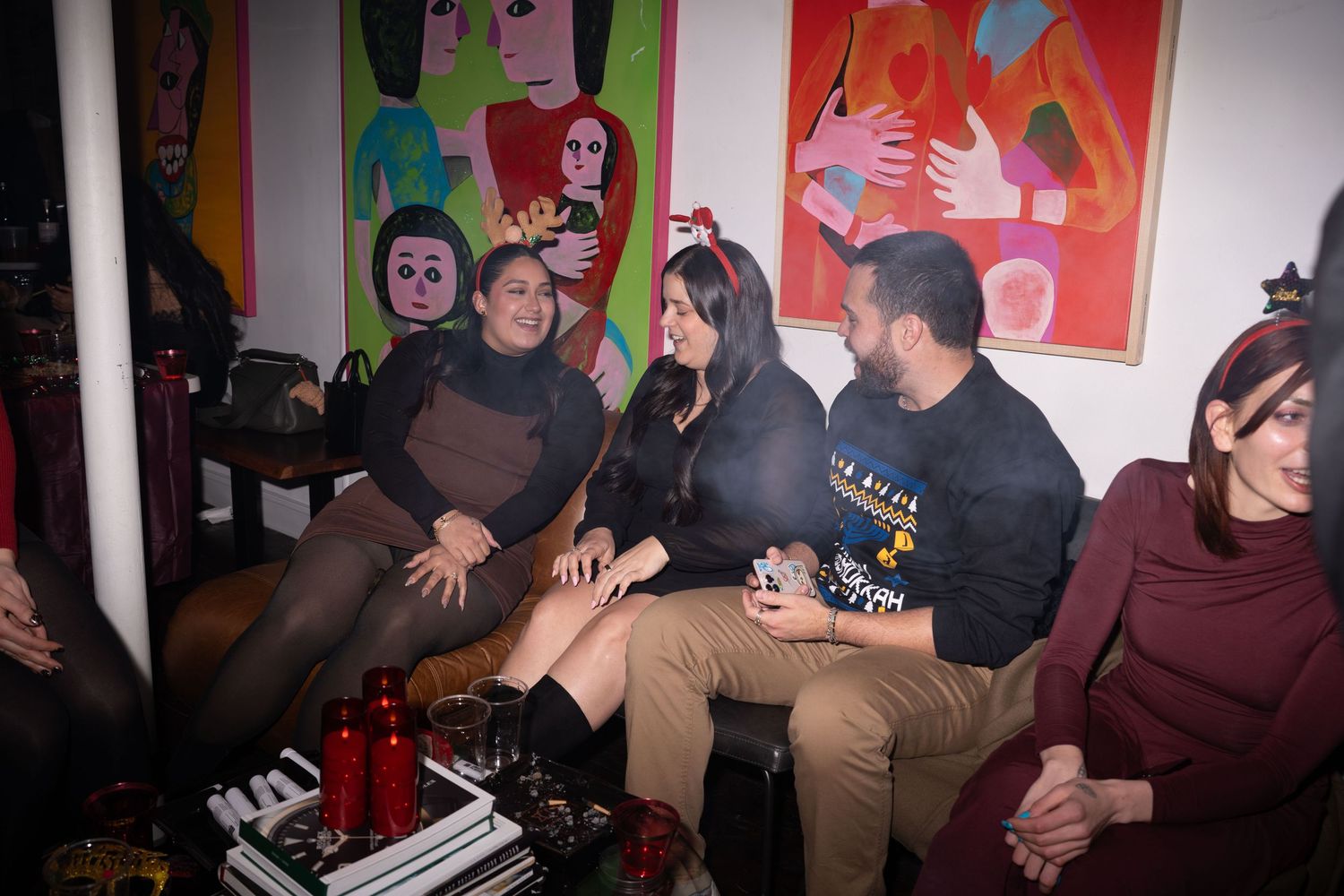 Group of friends socializing on a couch surrounded by colorful artwork.
