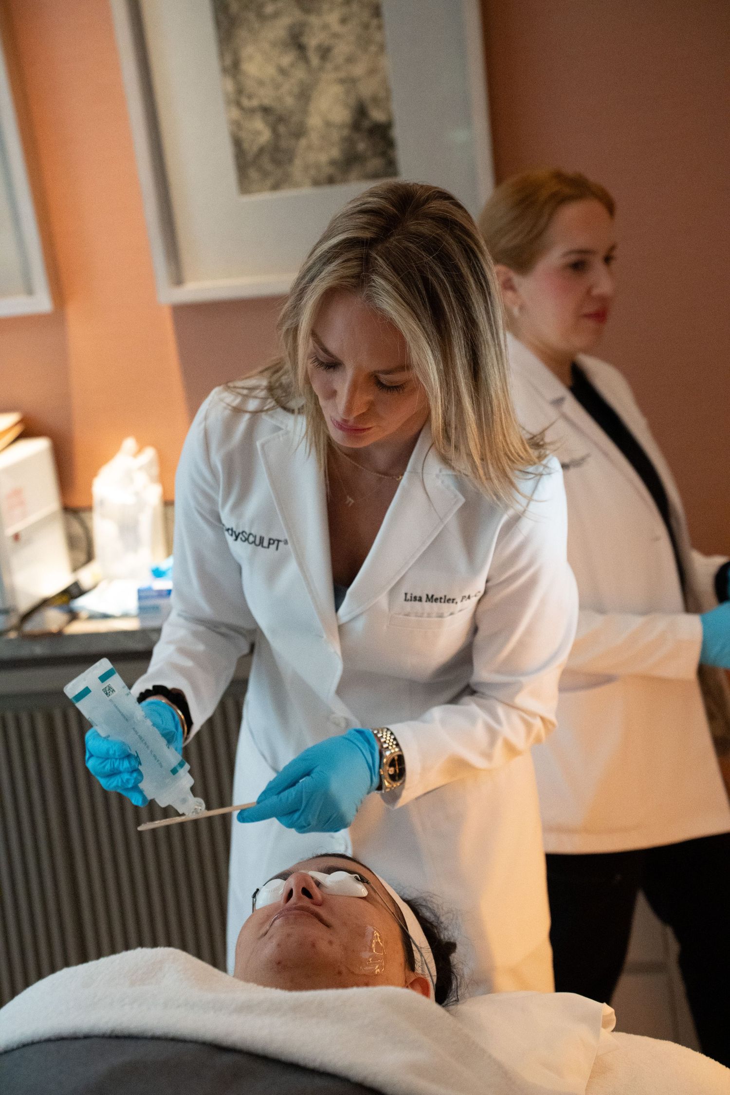 Medical professional in white lab coat performing a facial treatment on a patient in a clinical spa setting.