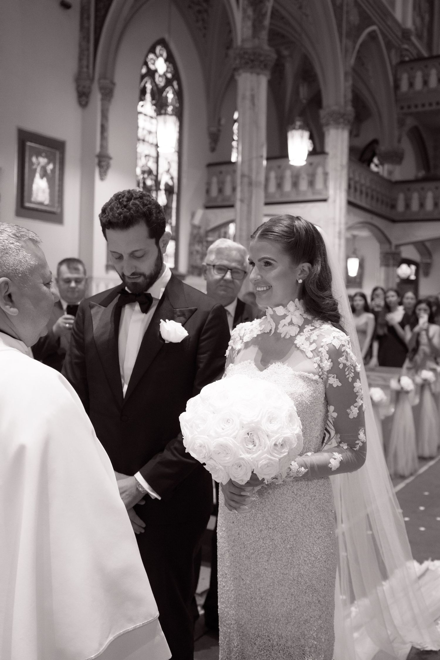 Bride and groom stand at the altar during a classic church wedding ceremony, bride holding white rose bouquet.