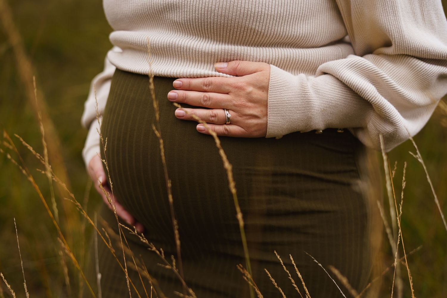 Close-up shots of hands gently touching tall grass in golden evening sunlight.