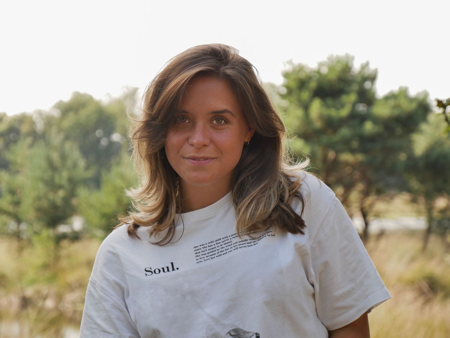 Portret in witte t-shirt met zonlicht op achtergrond.