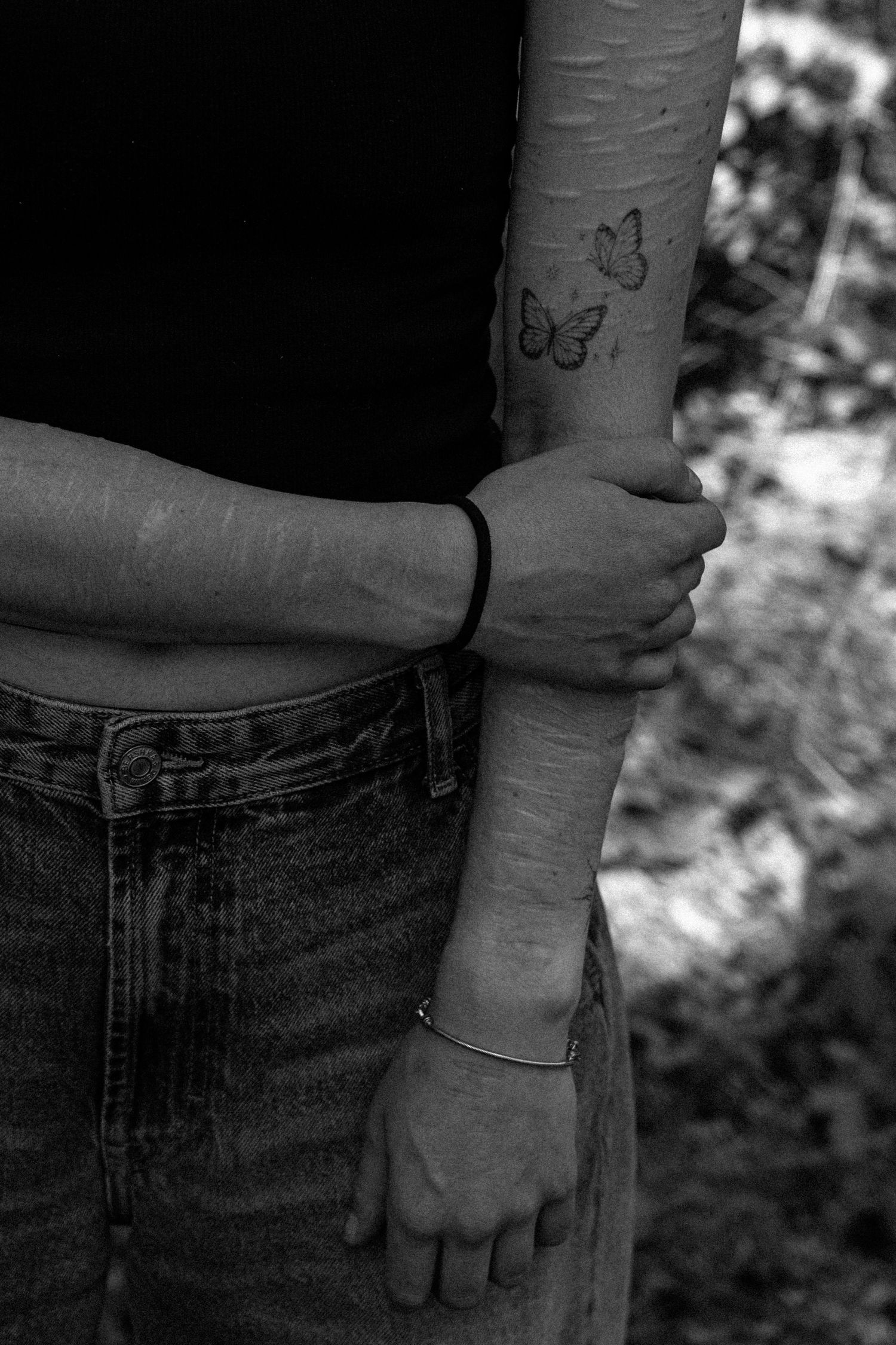 Arm met littekens en een vlinder tatoeages in zwart-wit.