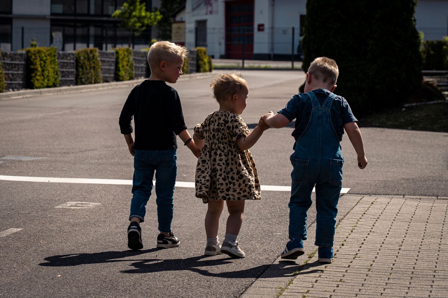 Drie kinderen wandelen hand in hand op zonnig pad.