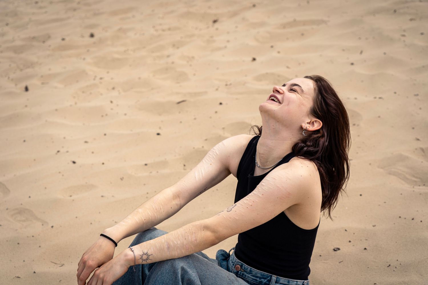 Persoon liggend op zandstrand met dramatische pose.