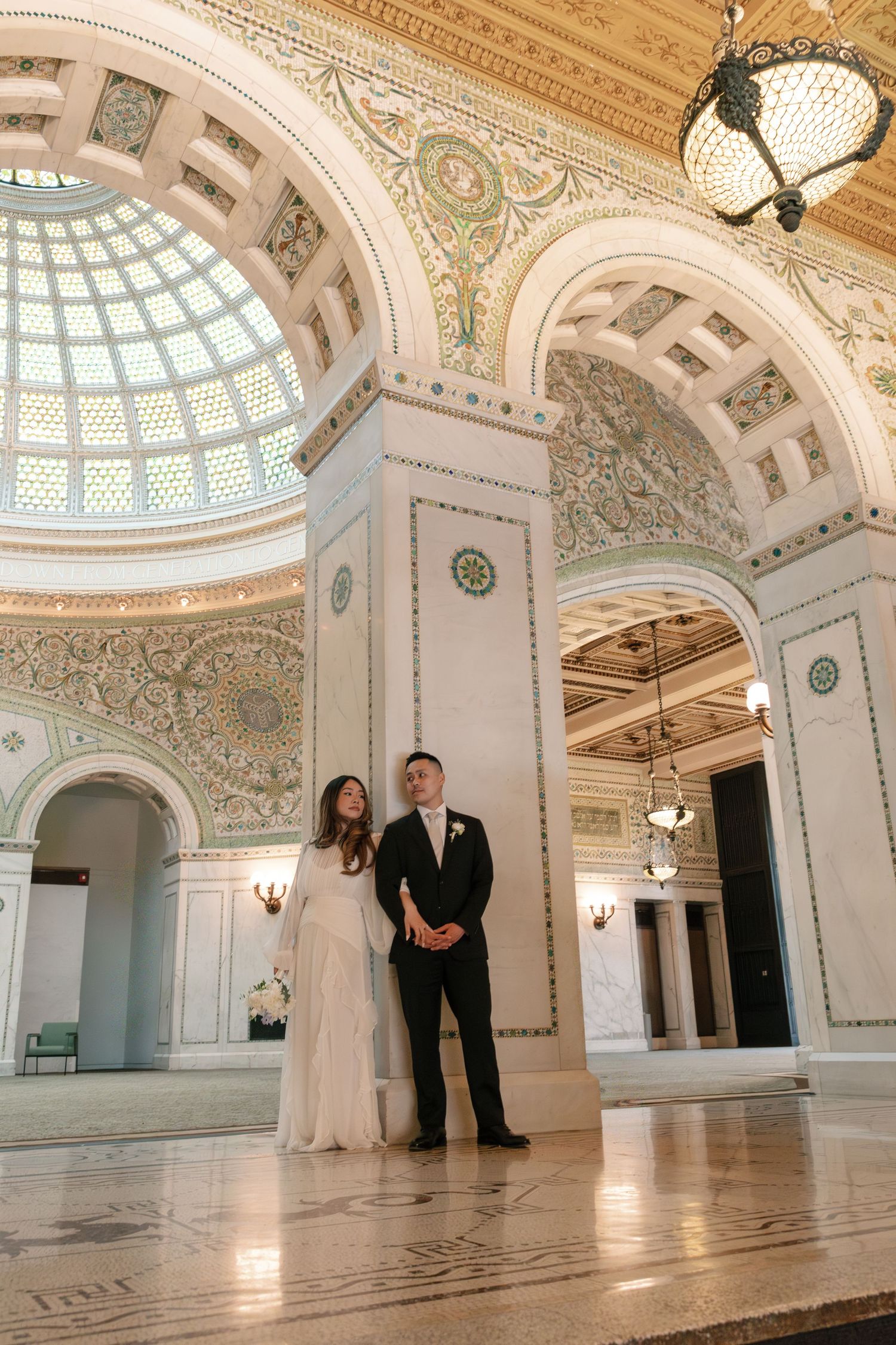 Elegant white and mint-colored historic ballroom with ornate domed ceiling, decorative columns and polished marble floors.