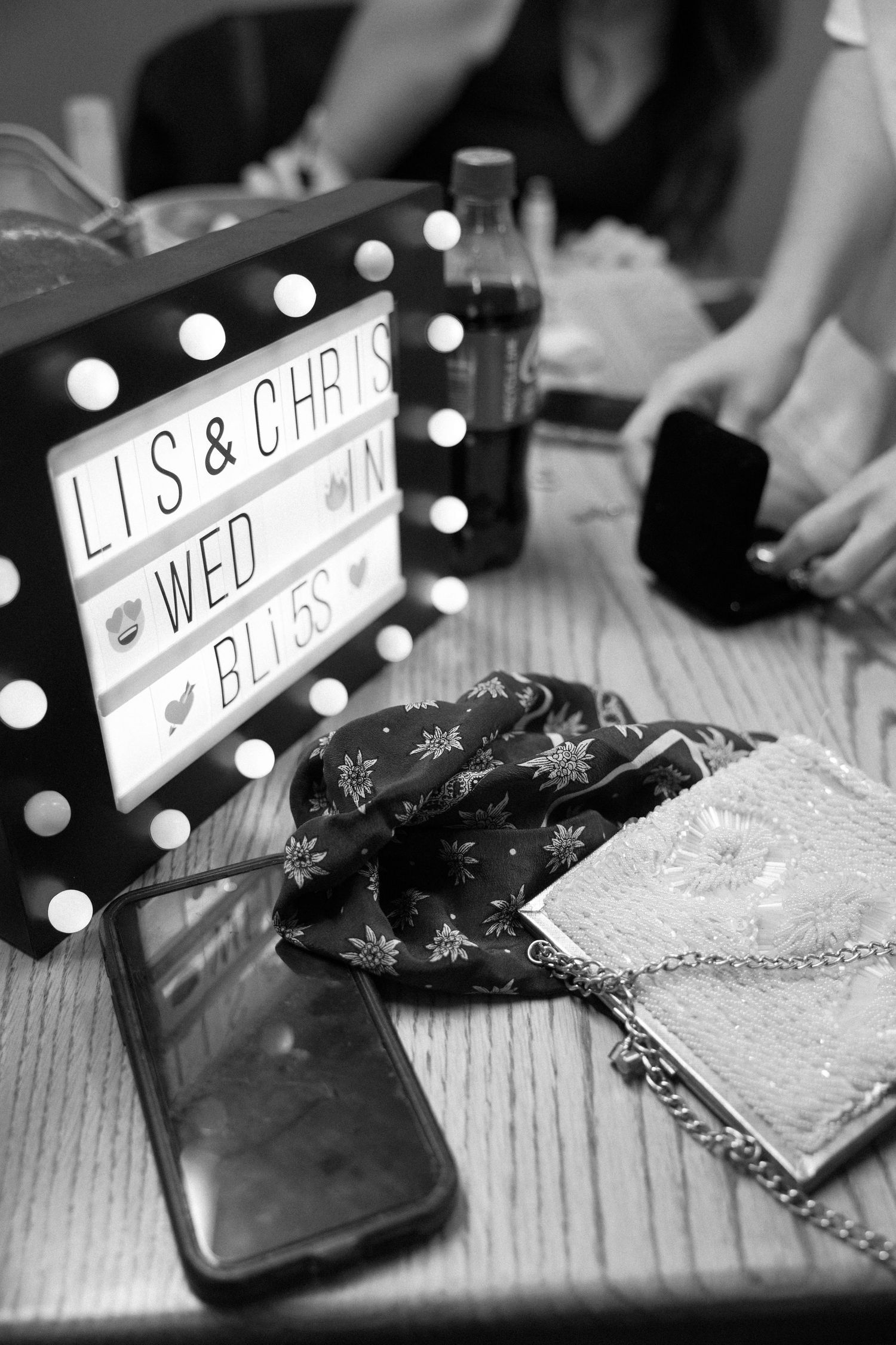 Black and white wedding detail shots showing illuminated name signs and decorative elements at a reception table.