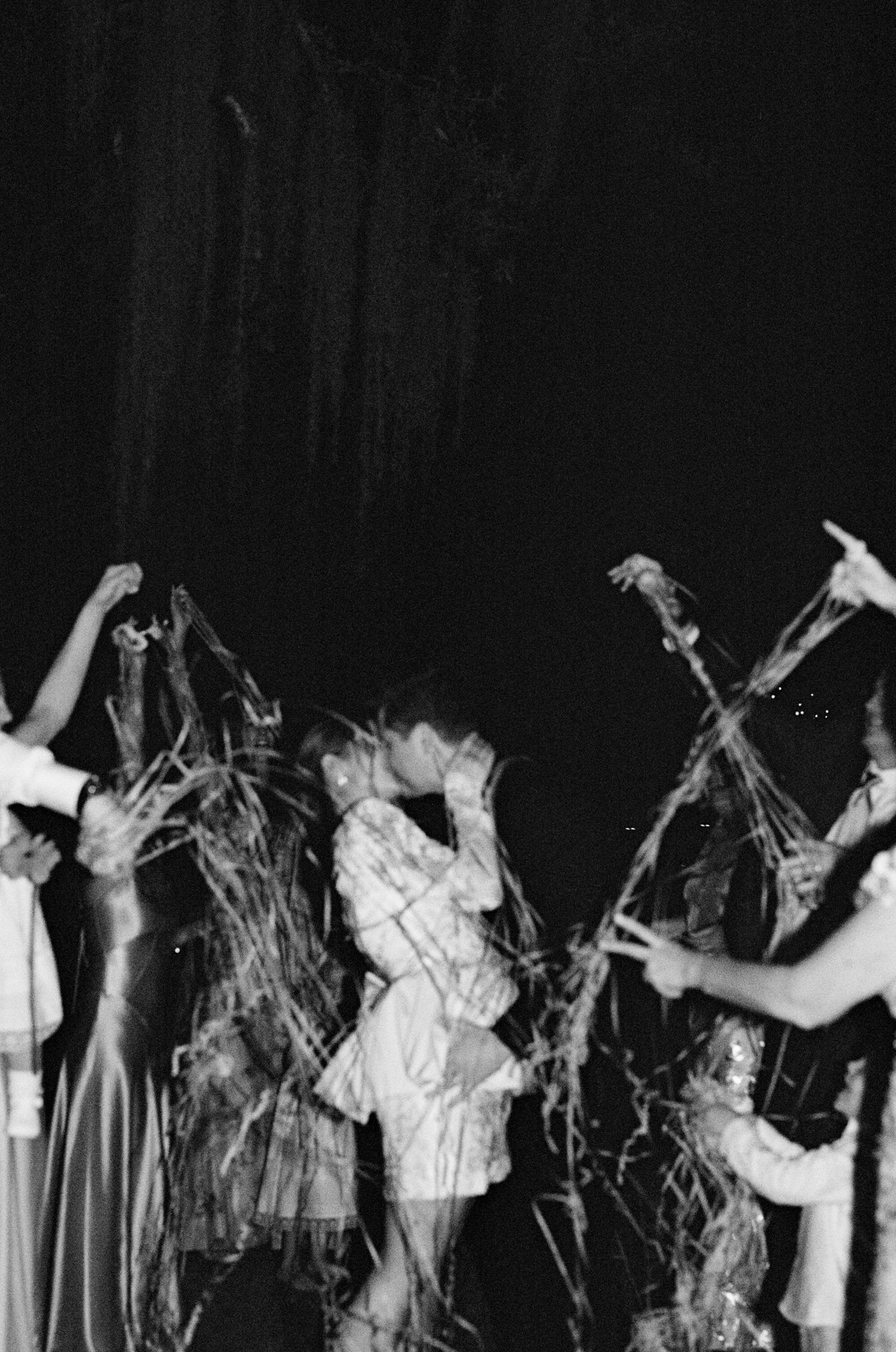 Black and white photo of people dancing and celebrating with streamers at a lively party event.