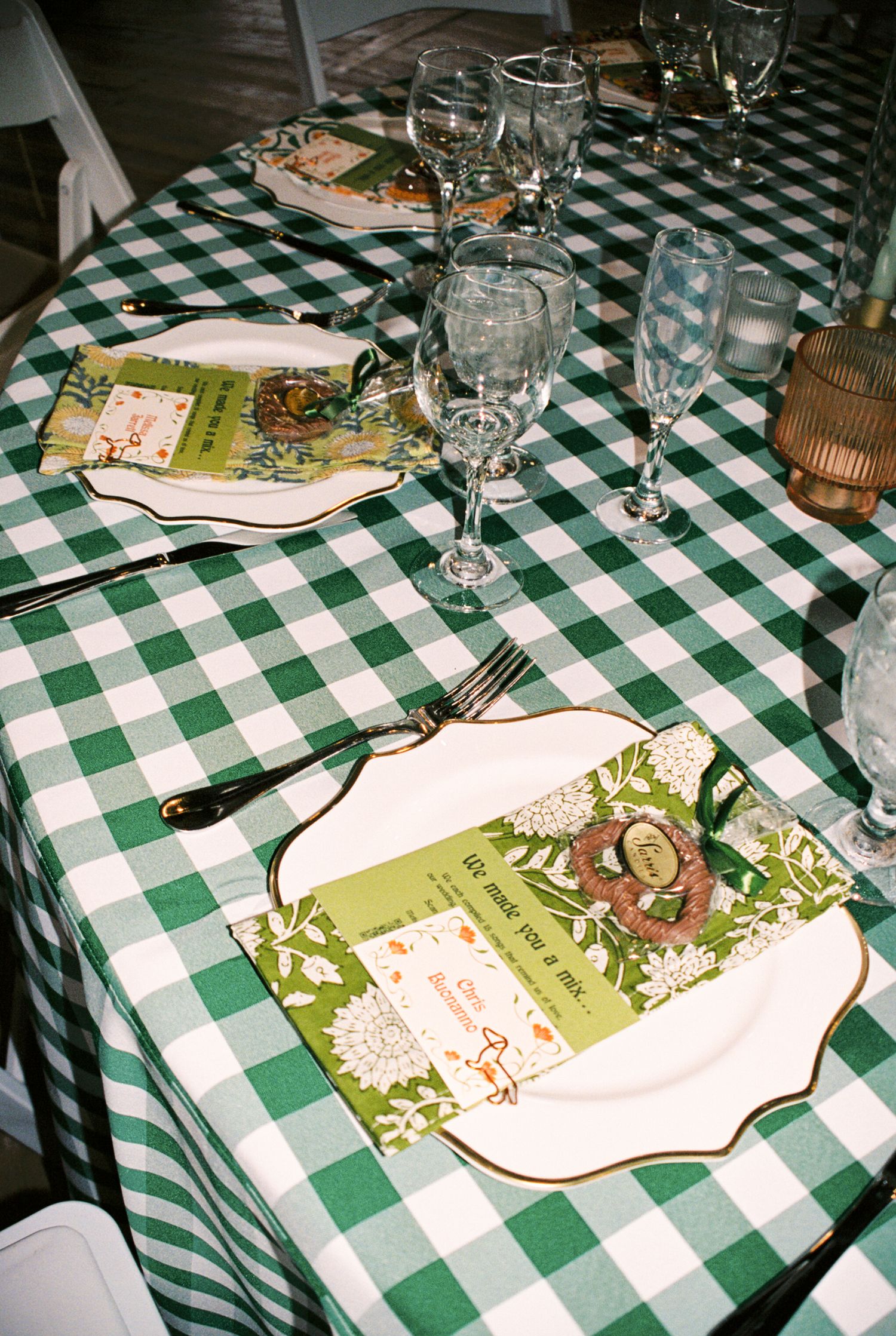 Place settings on a green and white checkered tablecloth with menus and wine glasses at an Italian restaurant.