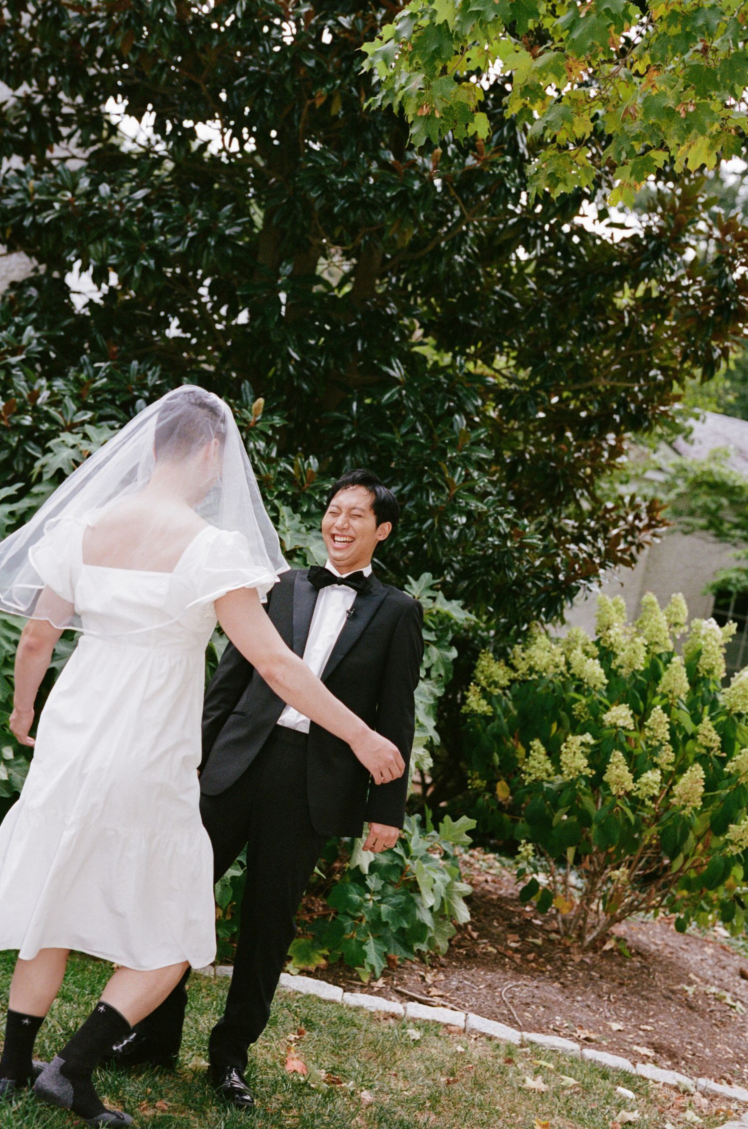 A series of candid wedding photos showing a couple playfully walking through a garden setting with greenery in the background.