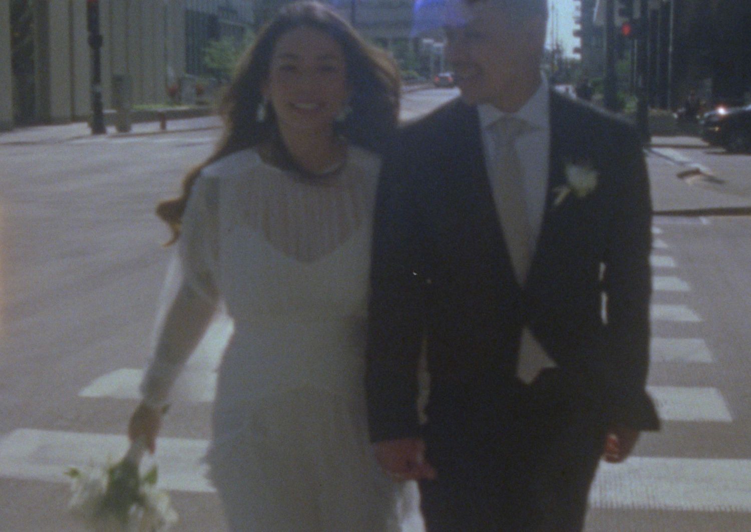 A wedding couple walks together down a pathway in formal attire during their special day.