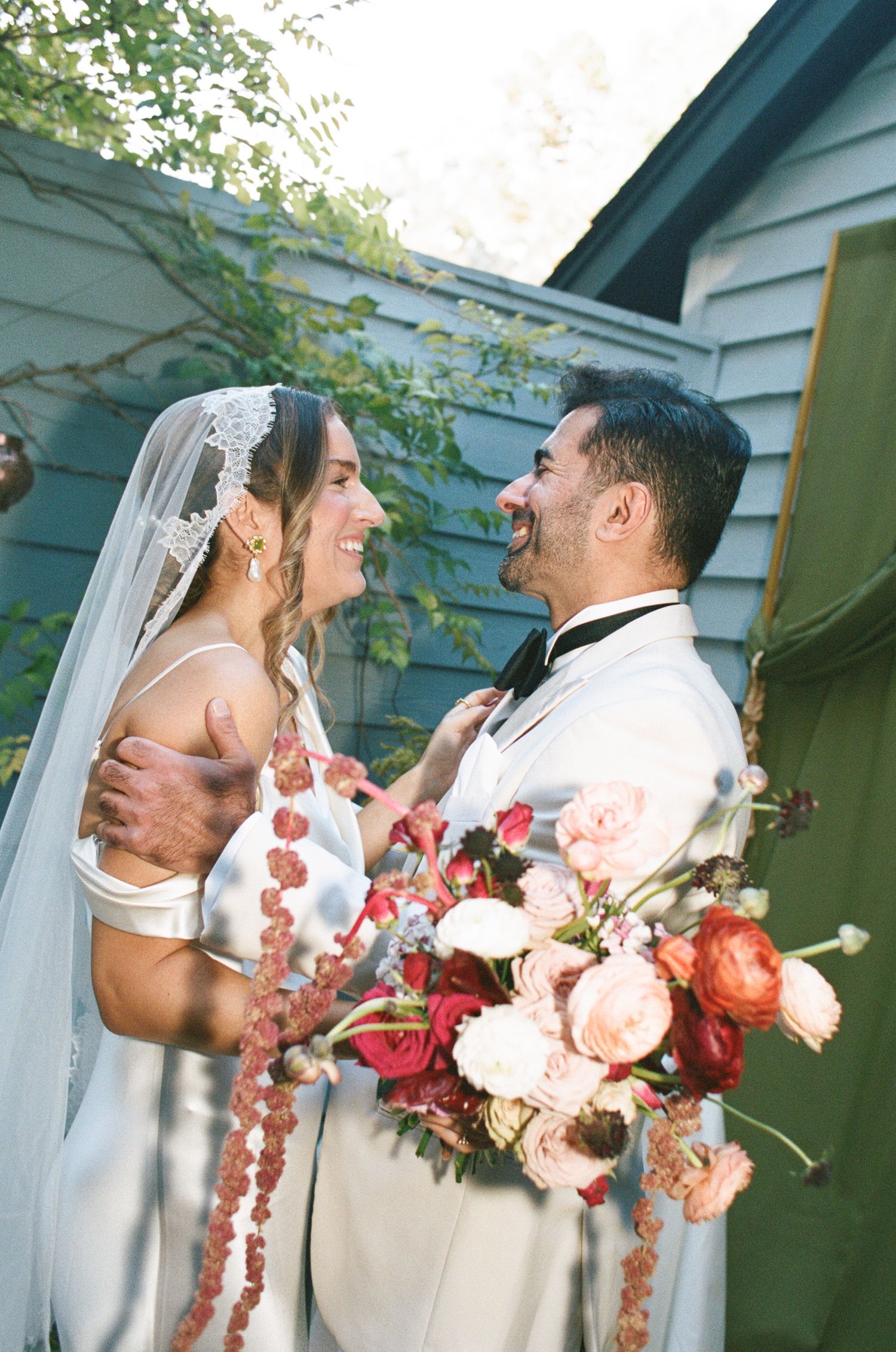 Romantic photo sequence shows a couple sharing intimate moments against white buildings with pink and coral flower bouquets.