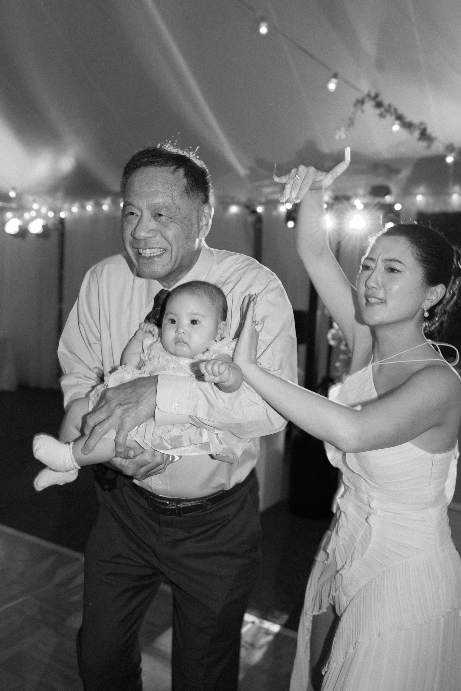 Black and white photo sequence shows joyful dance moments at a wedding reception with twinkling lights overhead.