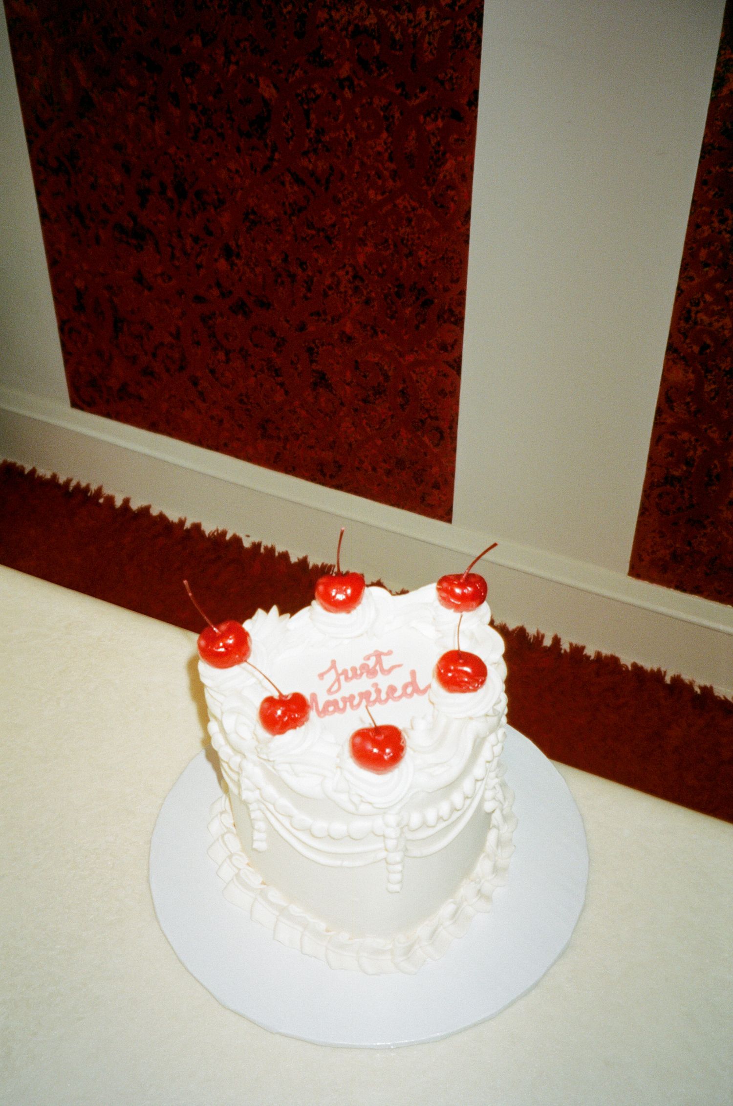 A sequence of white frosted cakes with red cherry toppings displayed against a red and white background.