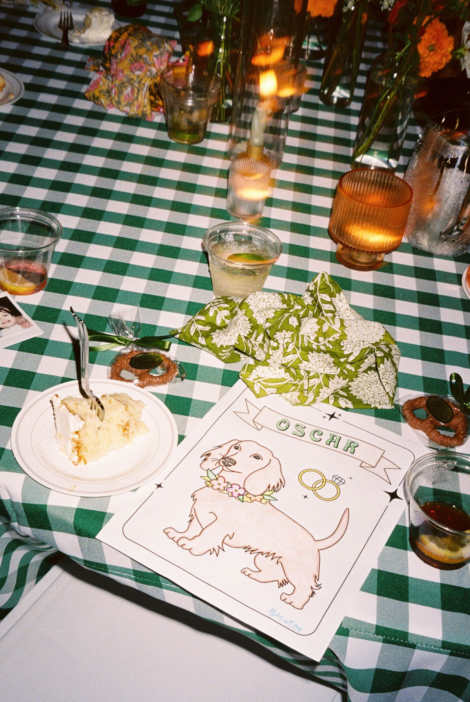 Place settings on a green and white checkered tablecloth with illustrated animal drawings and small floral centerpieces.