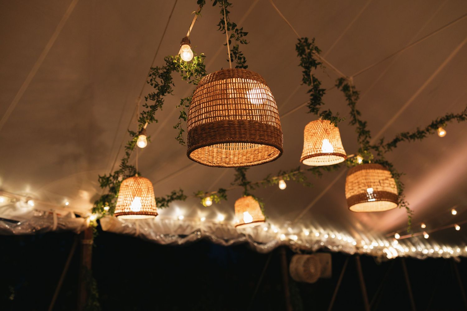 String lights and woven basket pendant lamps hang from a rustic ceiling creating a warm, cozy atmosphere.