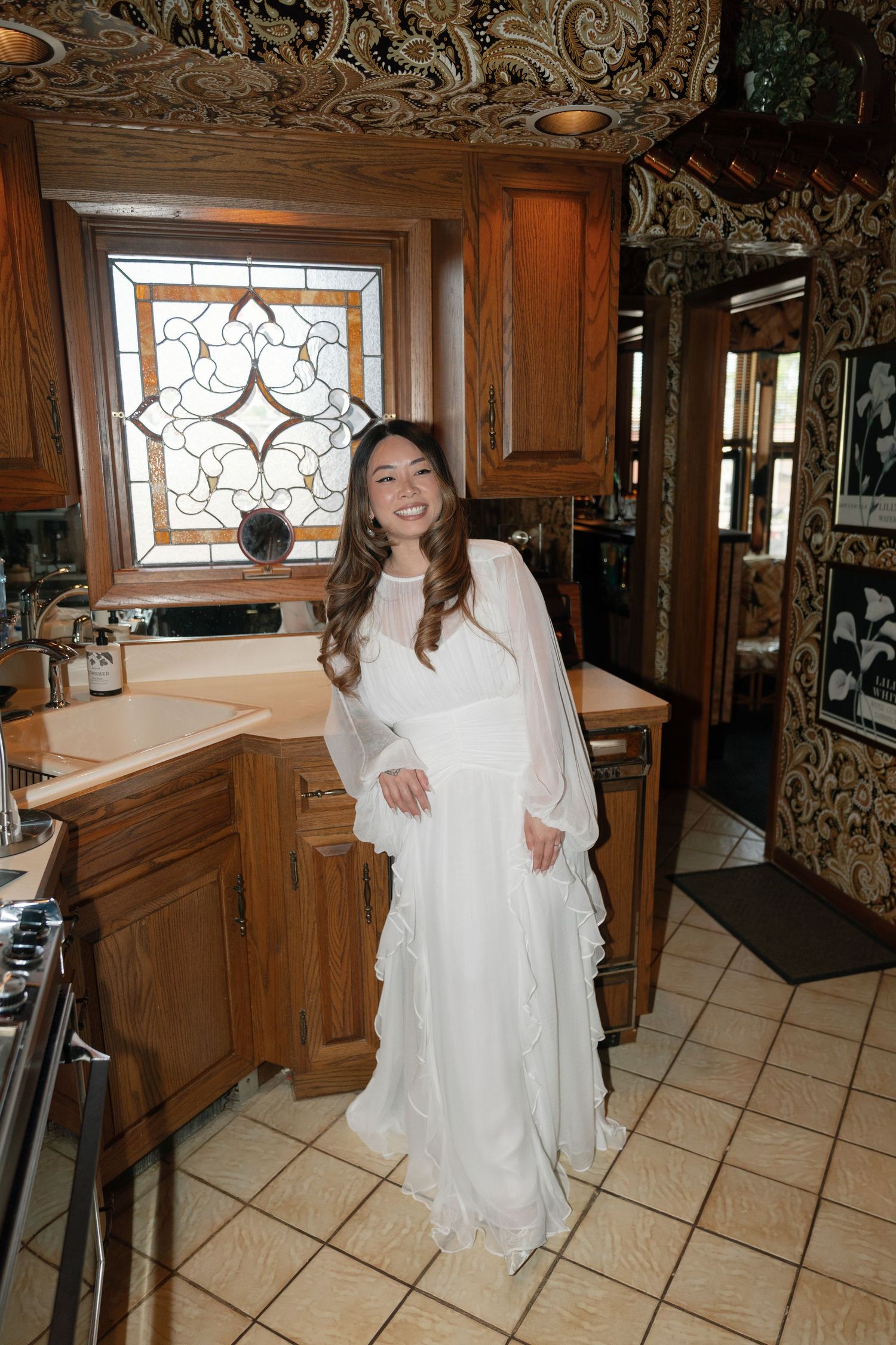 A series of photos showing someone in a white wedding dress posing in a kitchen with ornate wooden cabinetry and tile floors.