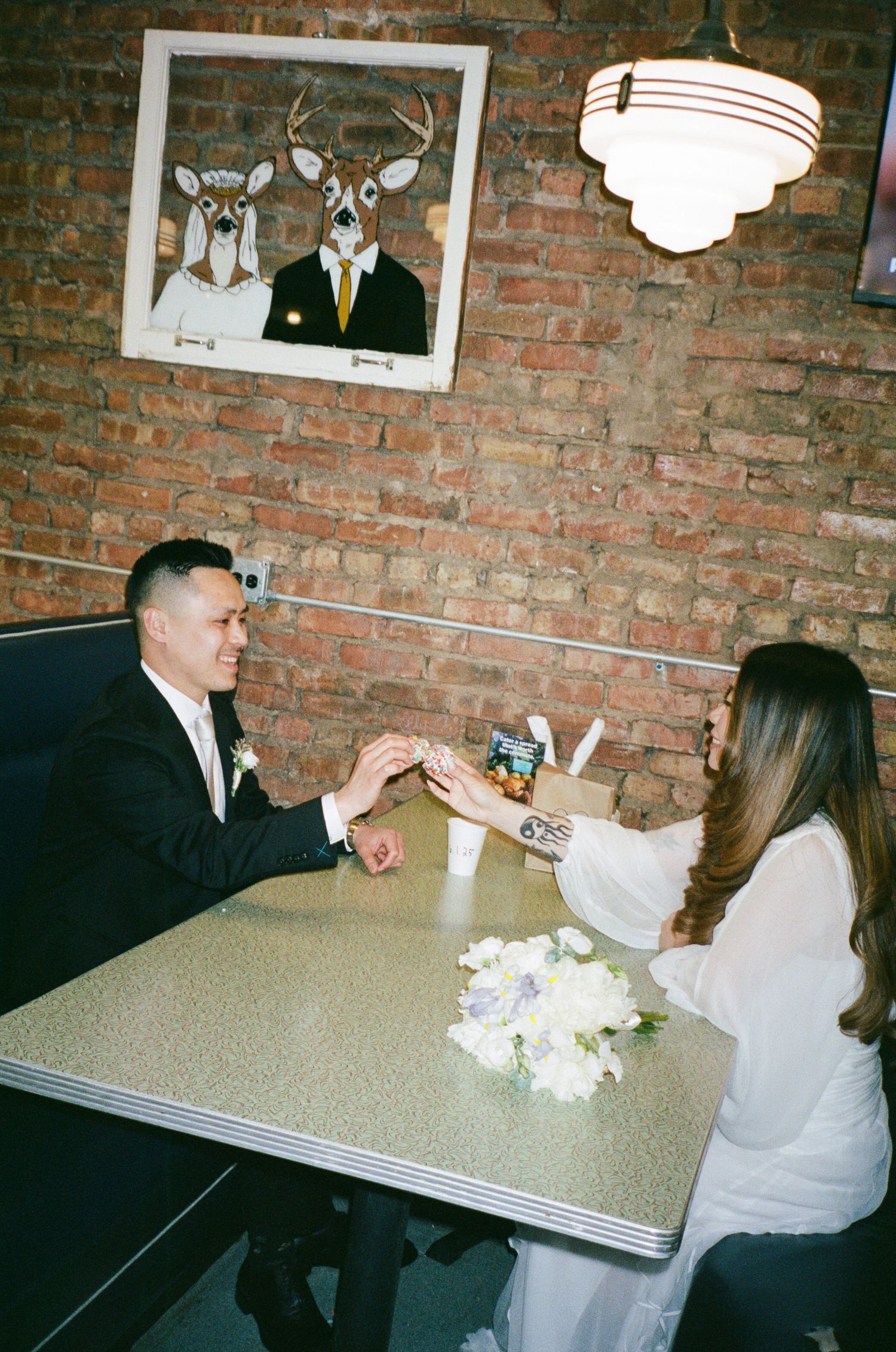 Three candid photos showing people seated at a table with a white bouquet against an exposed brick wall interior.