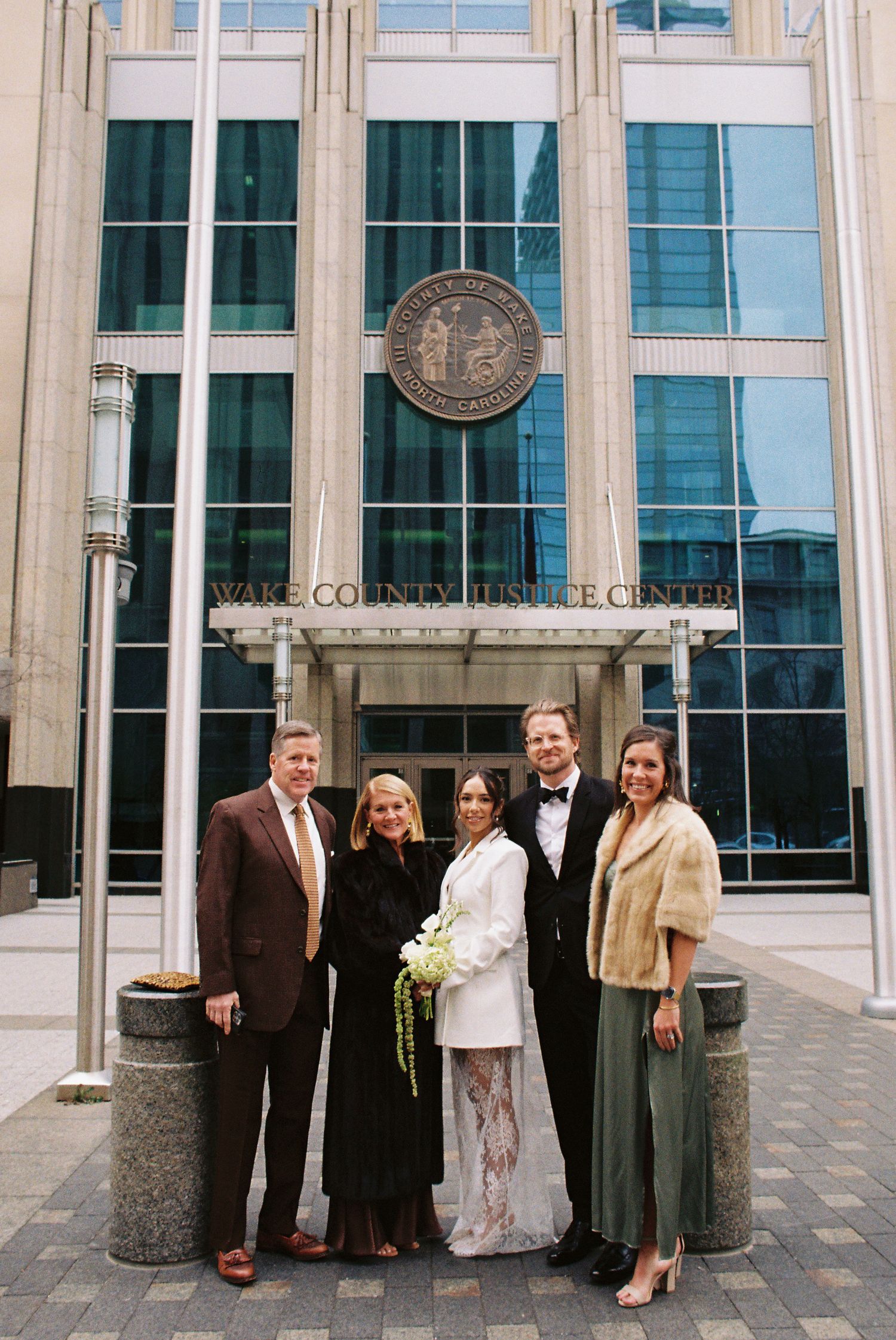 Bride and groom pose with family outside Wake County Justice Center after courthouse wedding ceremony.