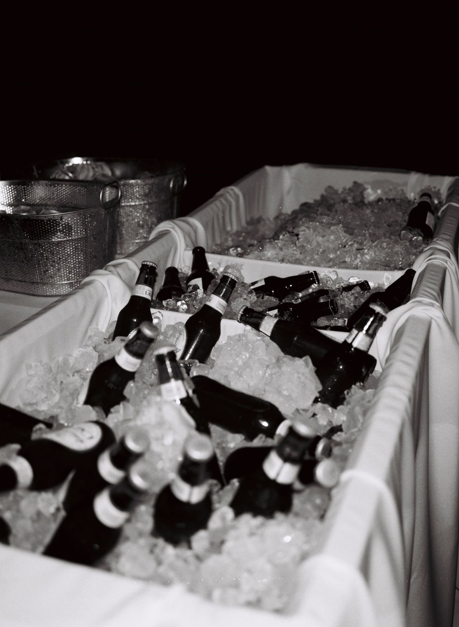 Black and white wine bottles chilling in ice at an event bar service setup.