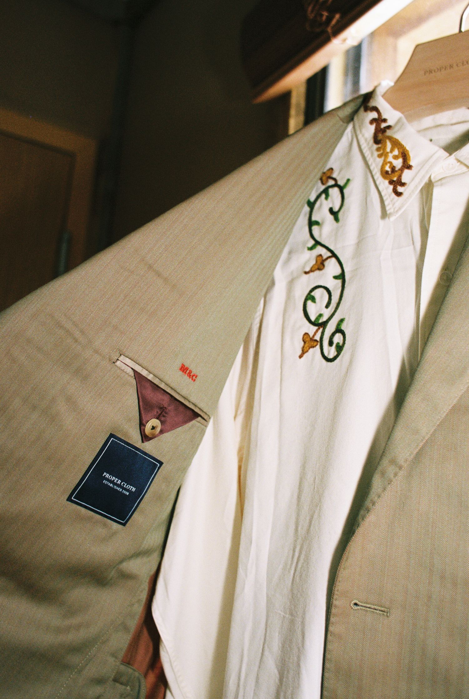 A series of white dress shirts hanging on clothing racks with price tags and labels attached.