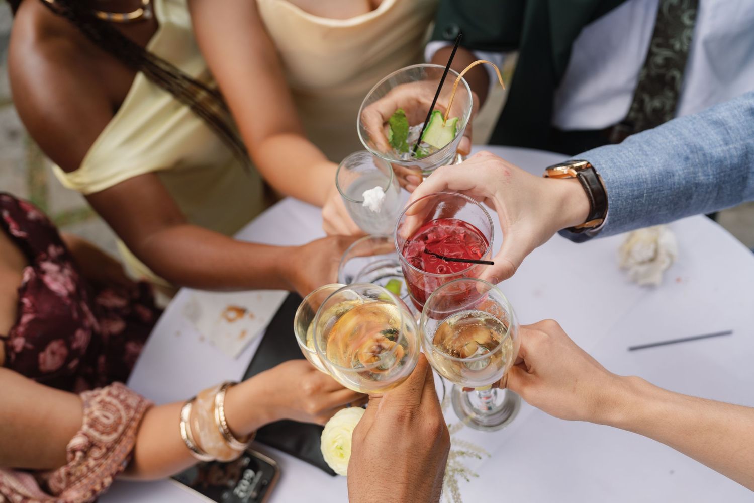 A group of people toasting with colorful cocktails and beverages at a social gathering.