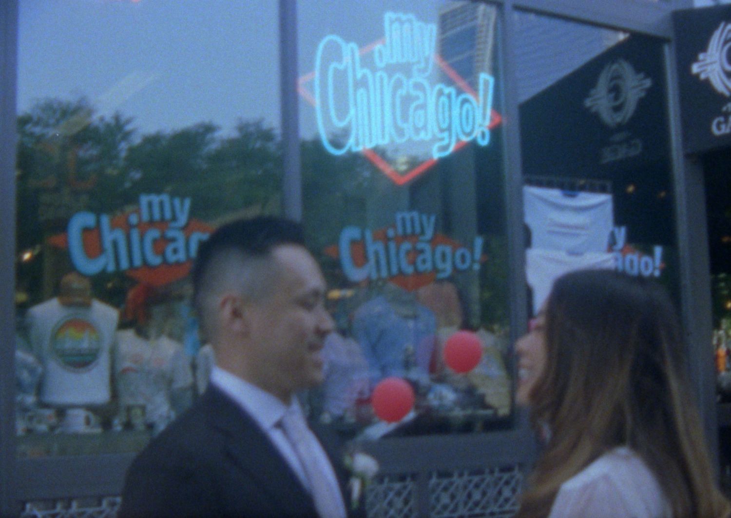A couple stands in conversation outside a storefront with bright neon 