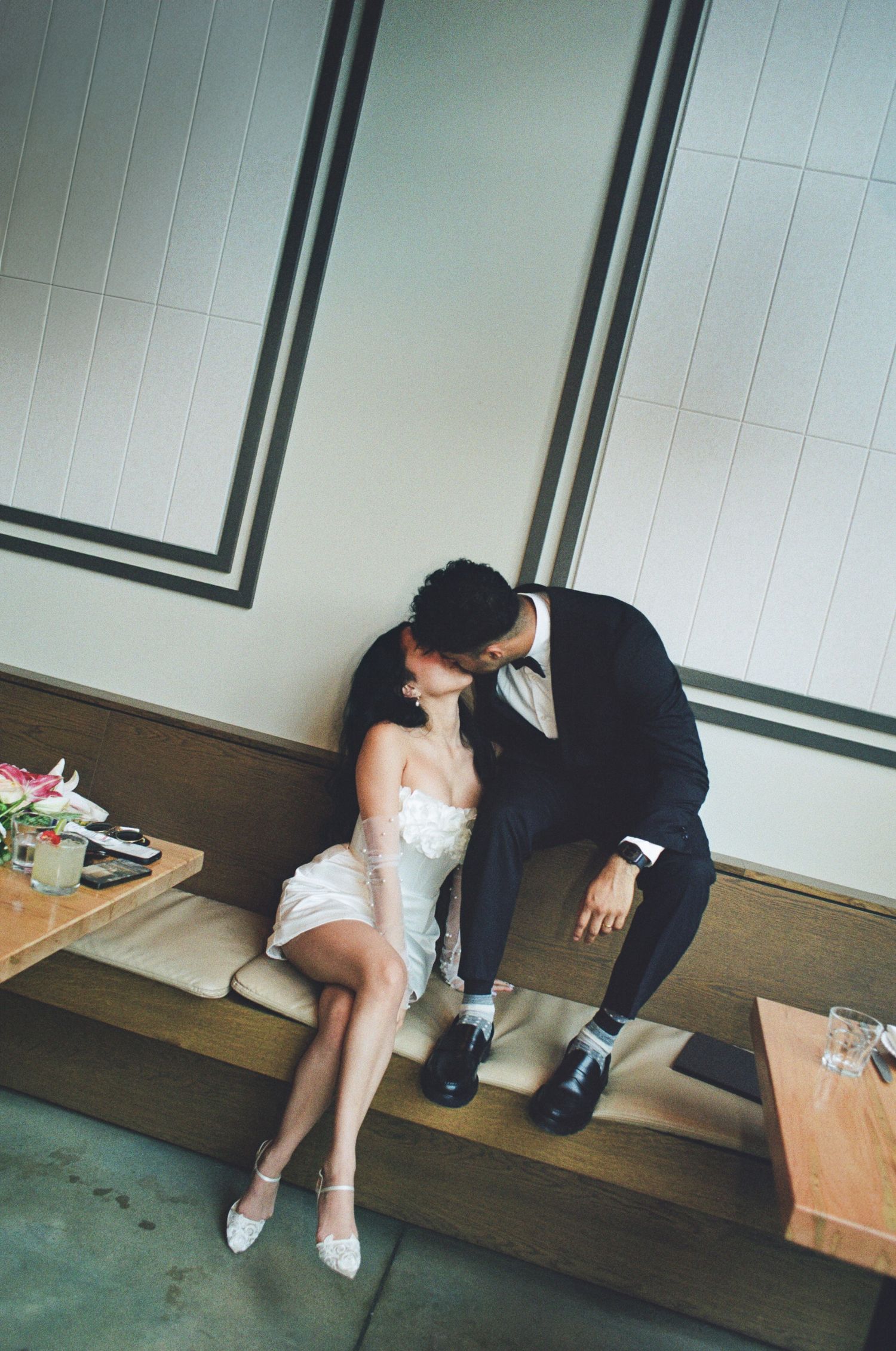 A tender moment between newlyweds sitting on wooden steps, with the bride in white and groom in a navy suit.